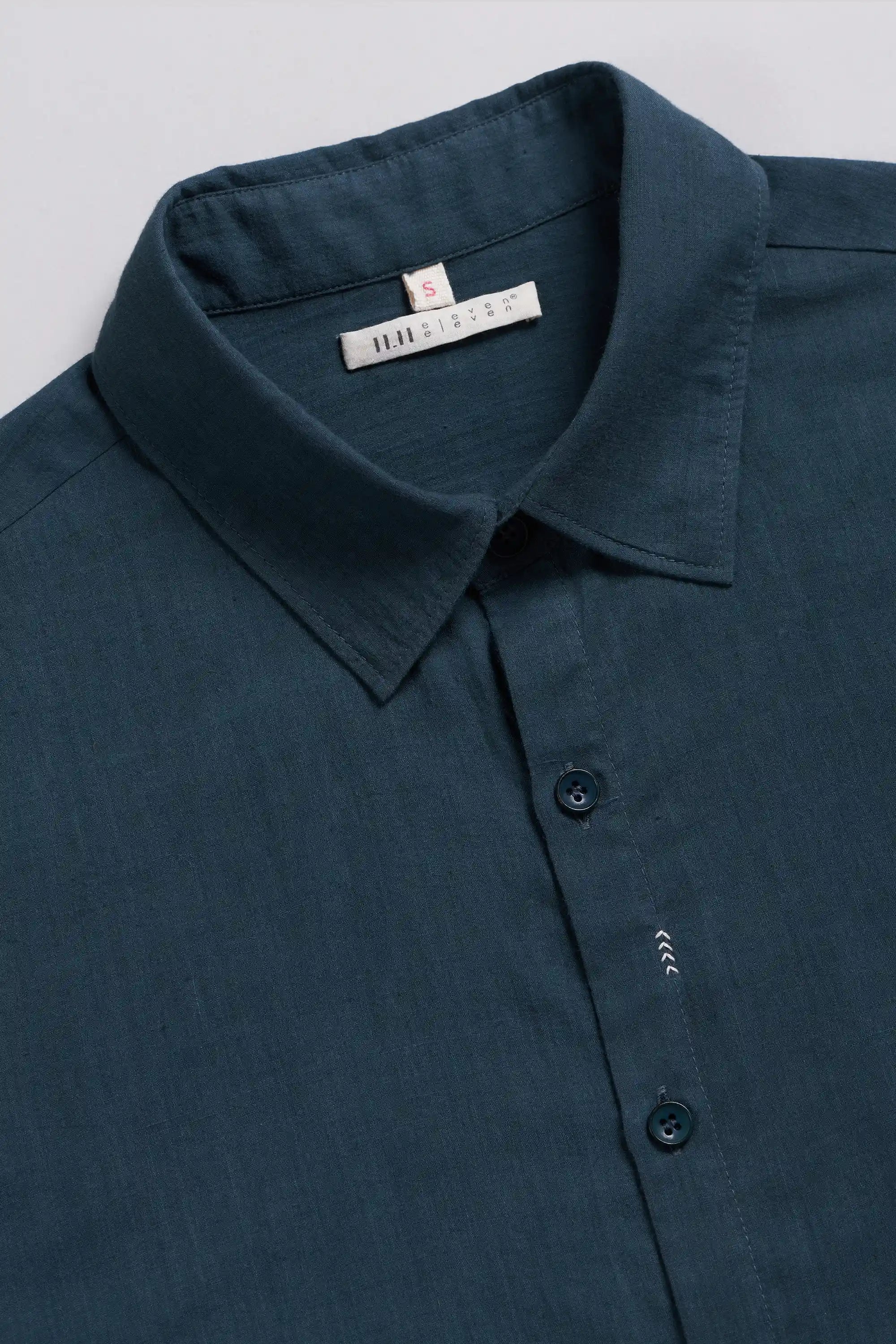 A close-up of a black indigo button-down shirt with a pointed collar.