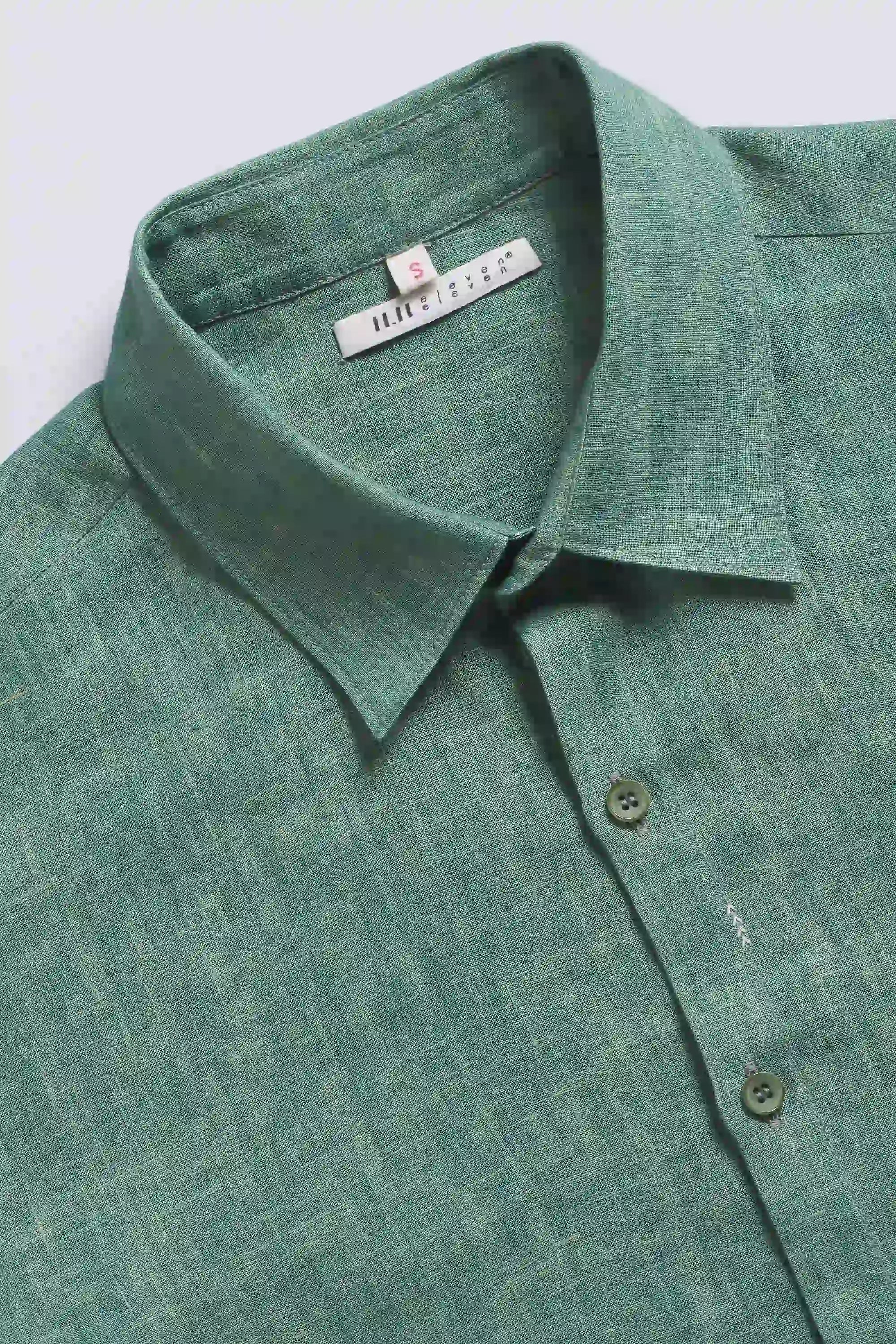 Close-up shot of a green shirt with collar and buttons on a light grey background