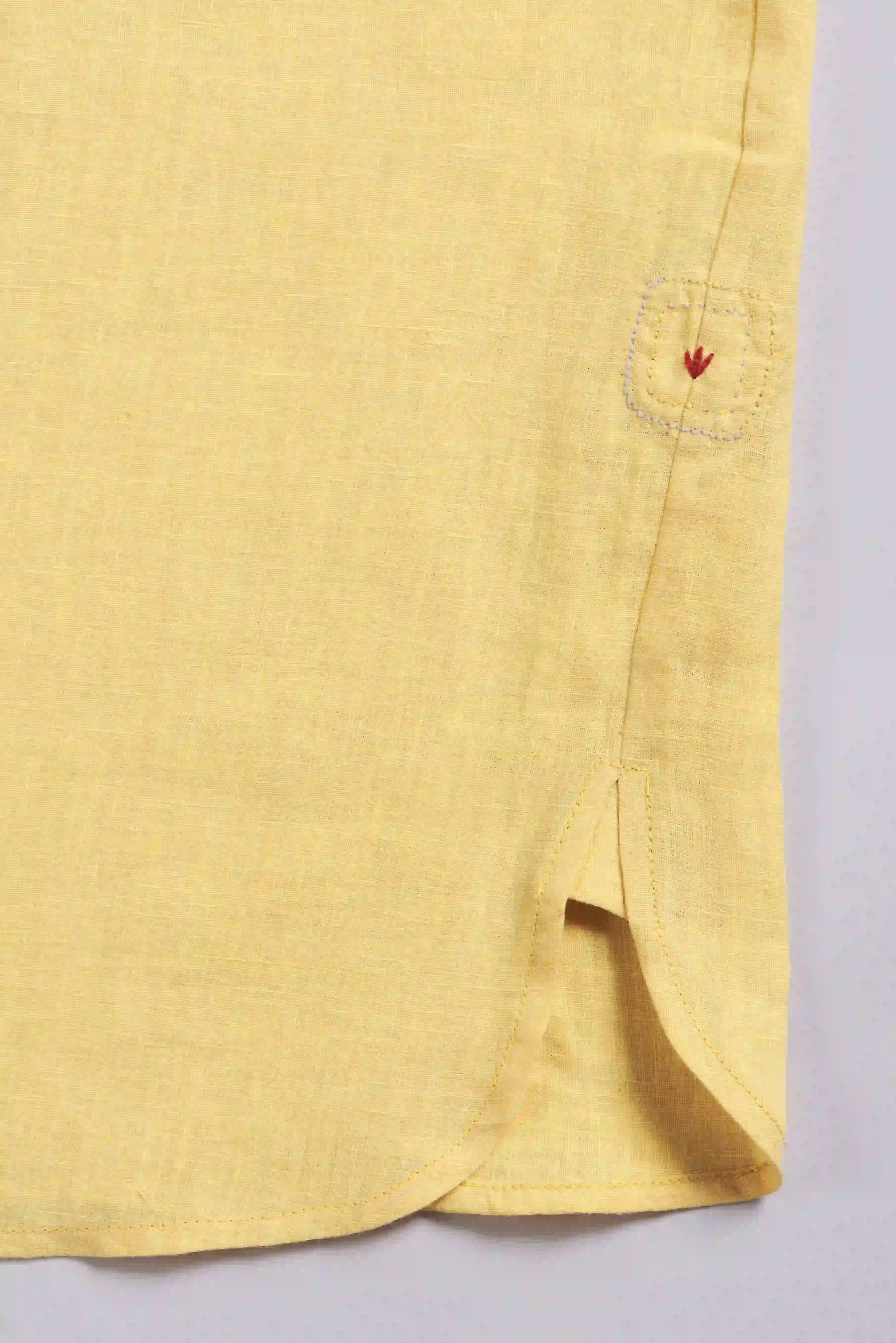 Close-up of a yellow shirt with pehchan on a light gray background