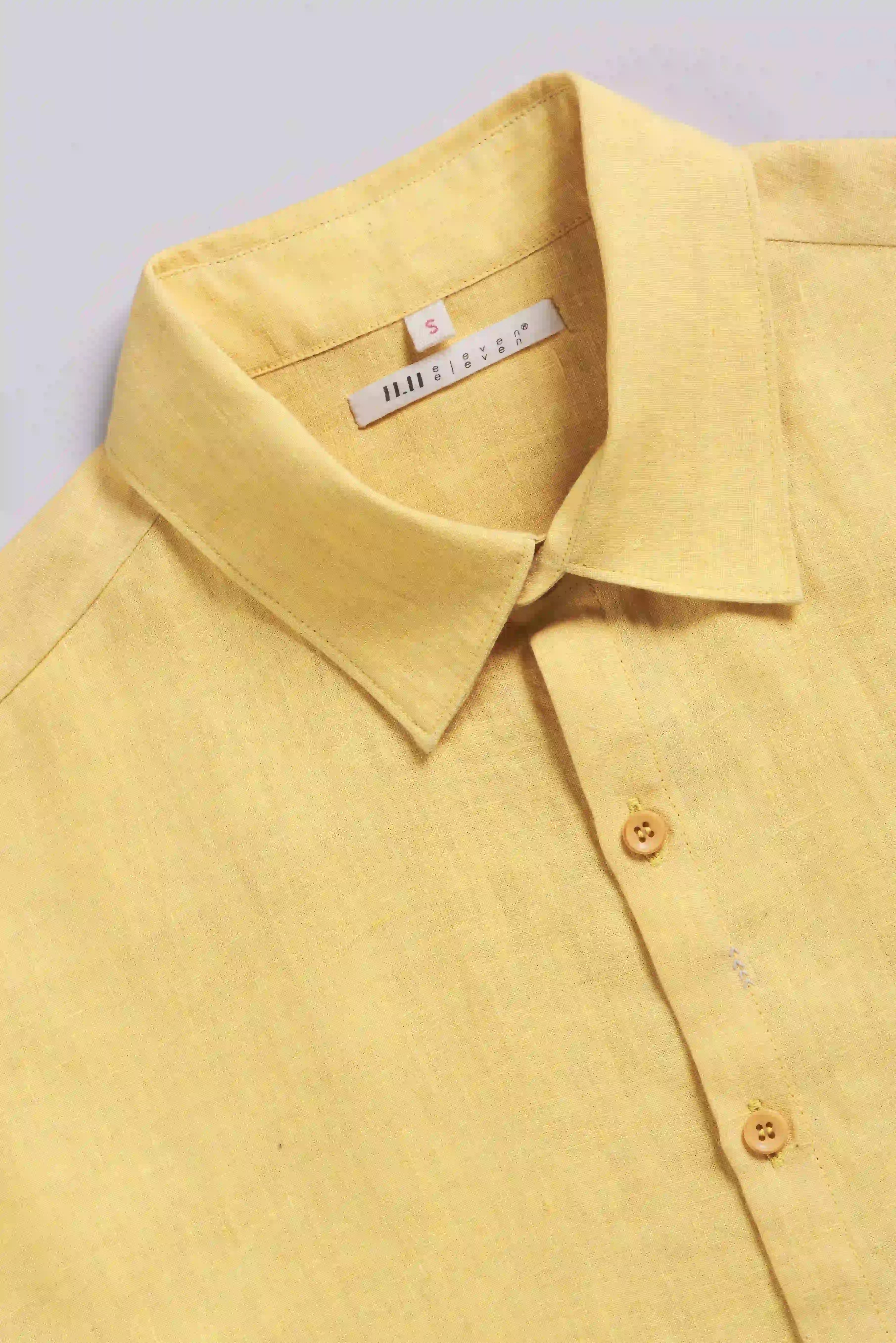 Yellow shirt with a collar and buttons on a light gray background
