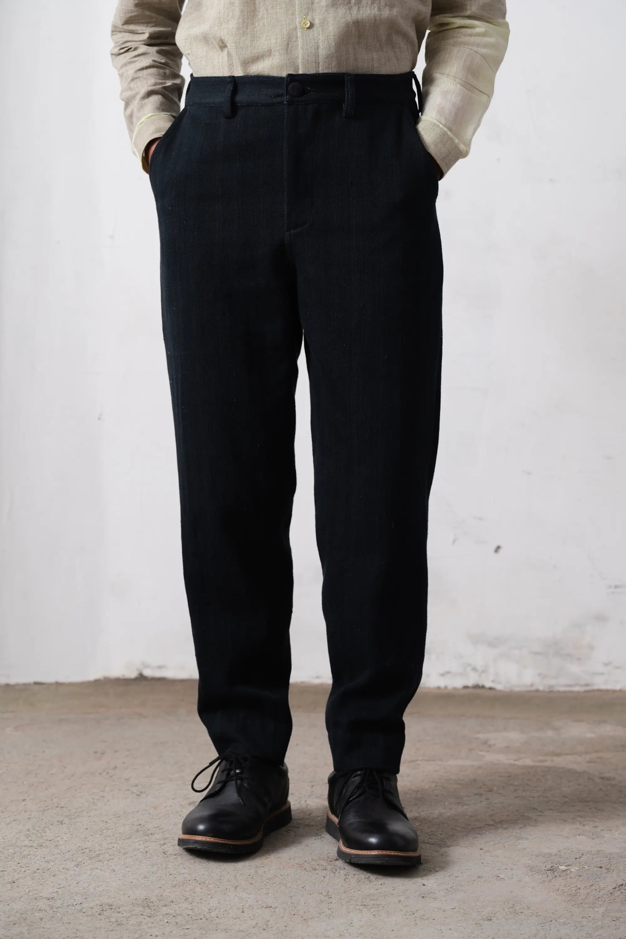 Man wearing midnight indigo pants and a shirt against a white wall.