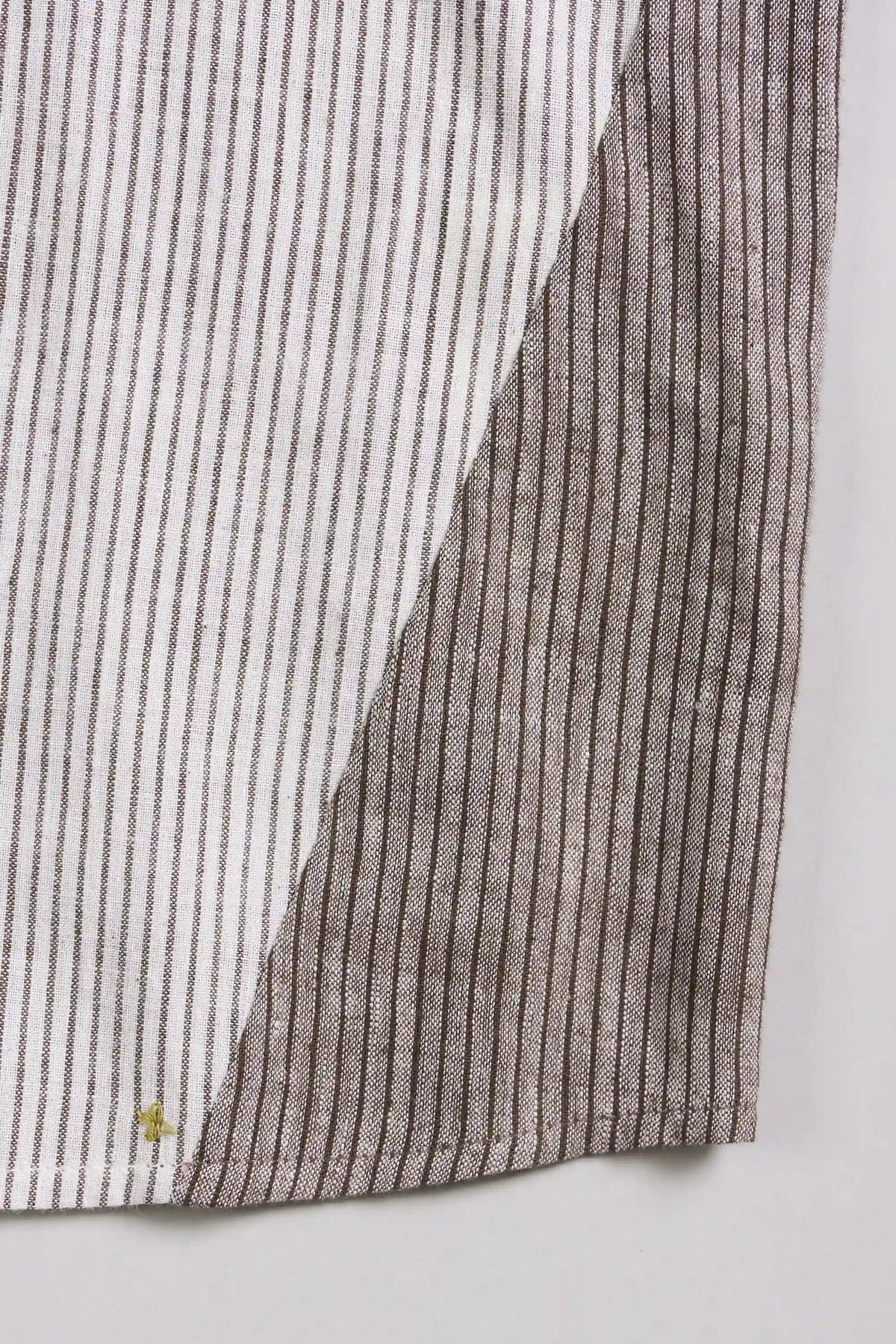 Close-up of a striped textile, likely a shirt or garment, showing alternating vertical stripe panels in white and taupe-grey.