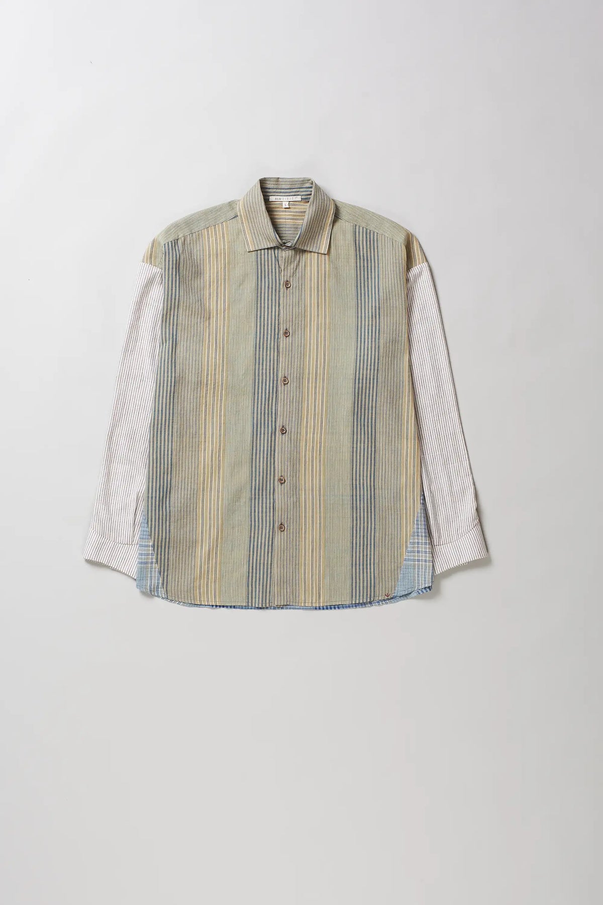 A long-sleeve button-up shirt with a vertical striped pattern in beige, blue, and yellow, featuring solid light-colored sleeves, laid flat against a light grey background.