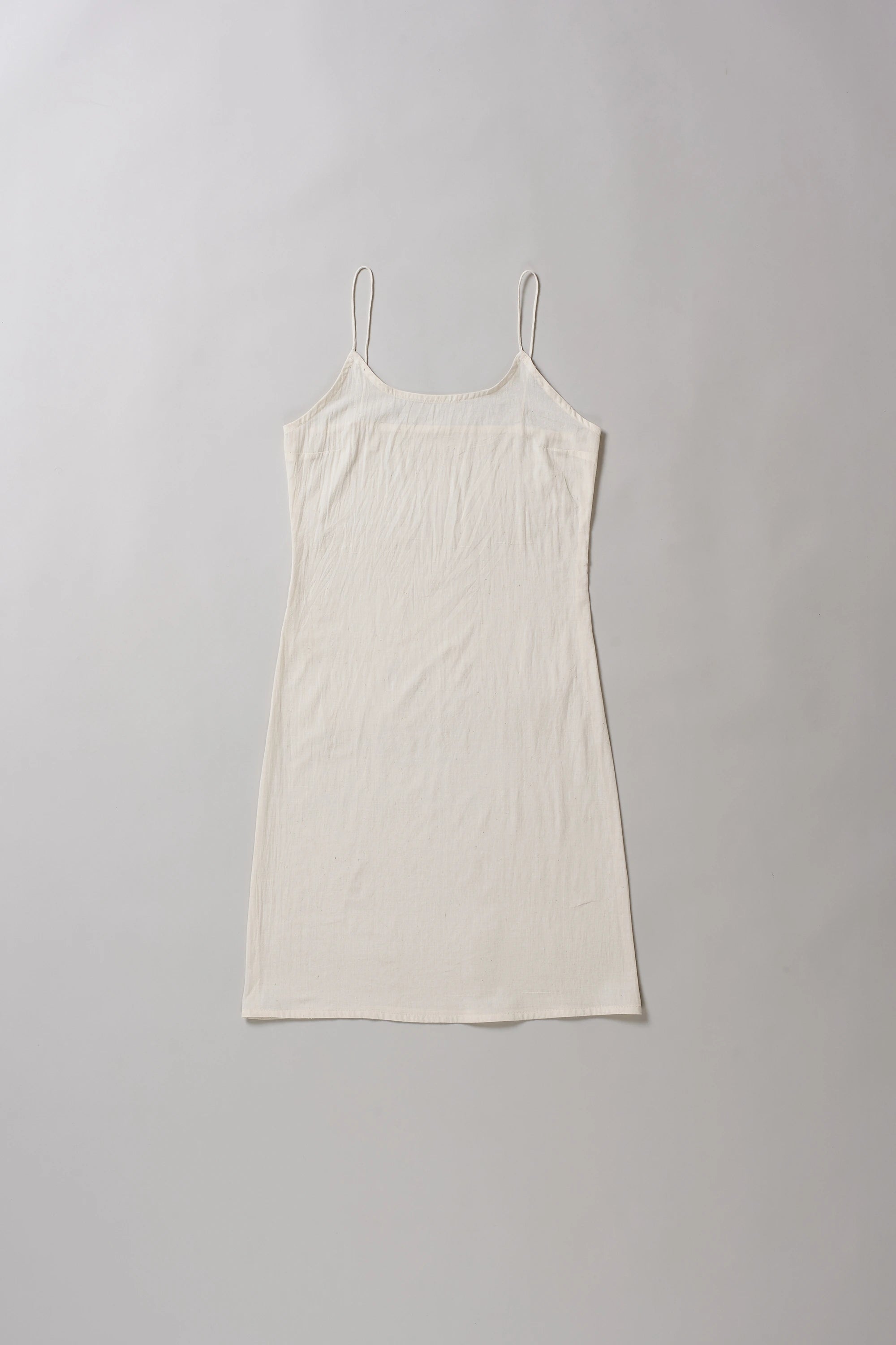 Ecru cotton slip dress on a grey background