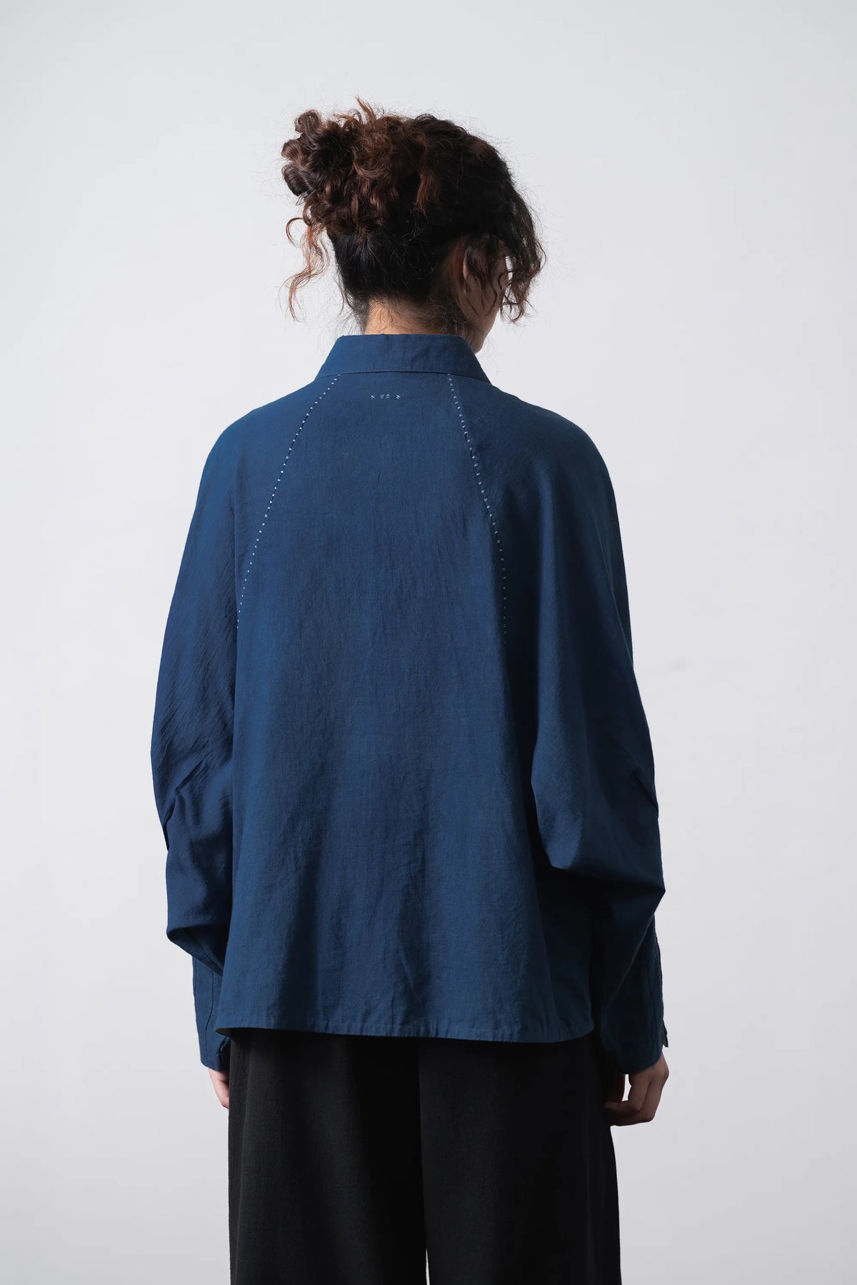 Back shot wearing of a cotton medium indigo shirt with hand details
