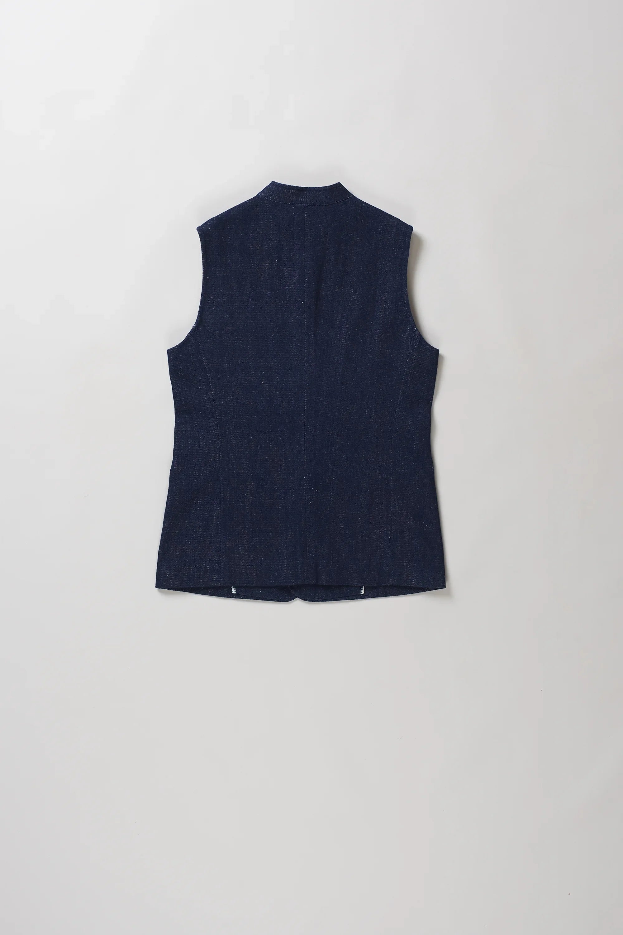 Back shot of sleeveless black indigo vest with a mandarin collar and front button closure, laid flat against a light gray background.