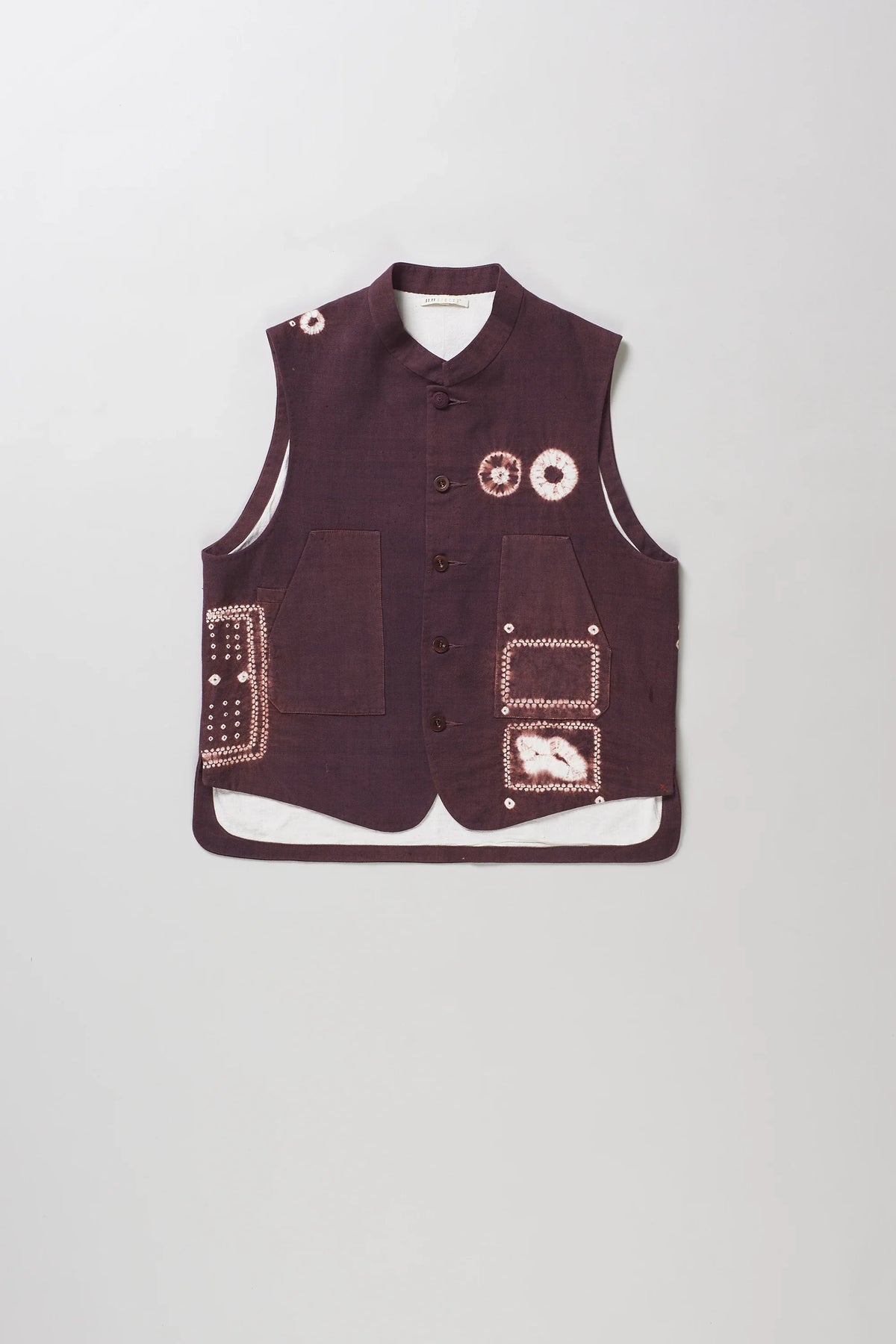 A sleeveless vest with shibori details, button front, and multiple patch pockets, shown flat against a light grey background.