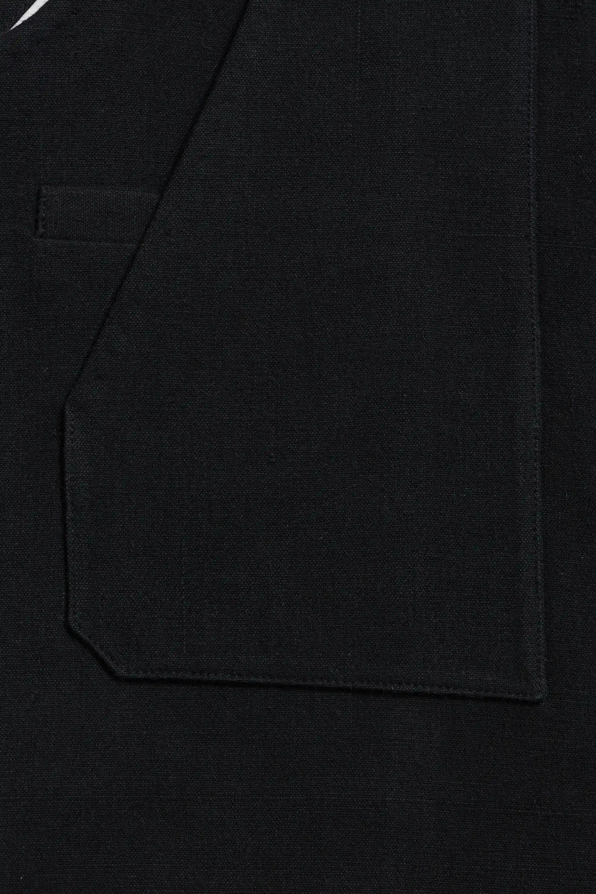 Close-up of a black fabric garment showing a pocket and stitched edge detail.