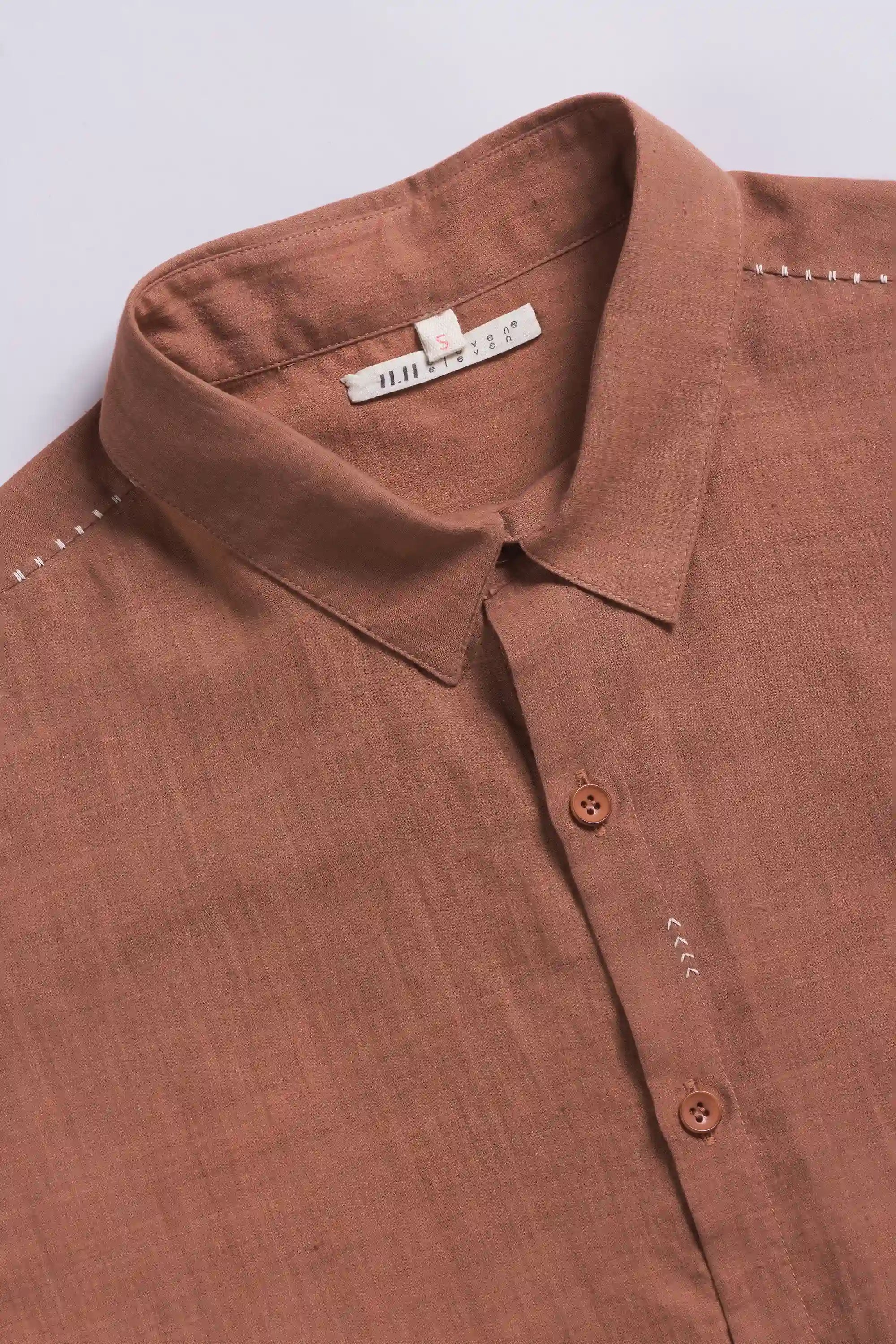 Close-up of a orange rust  shirt with a collar and buttons on a light grey back ground