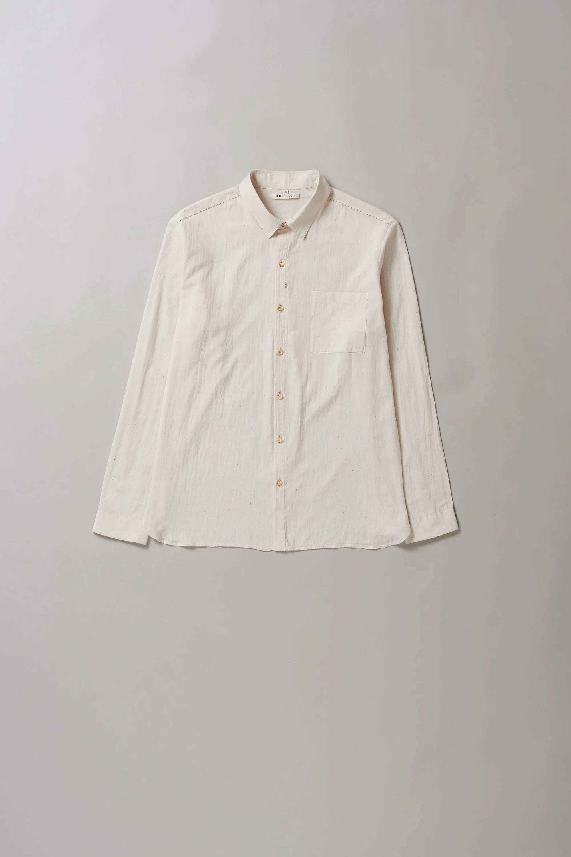 Front image of ecru shirt with hand detailing on a grey background