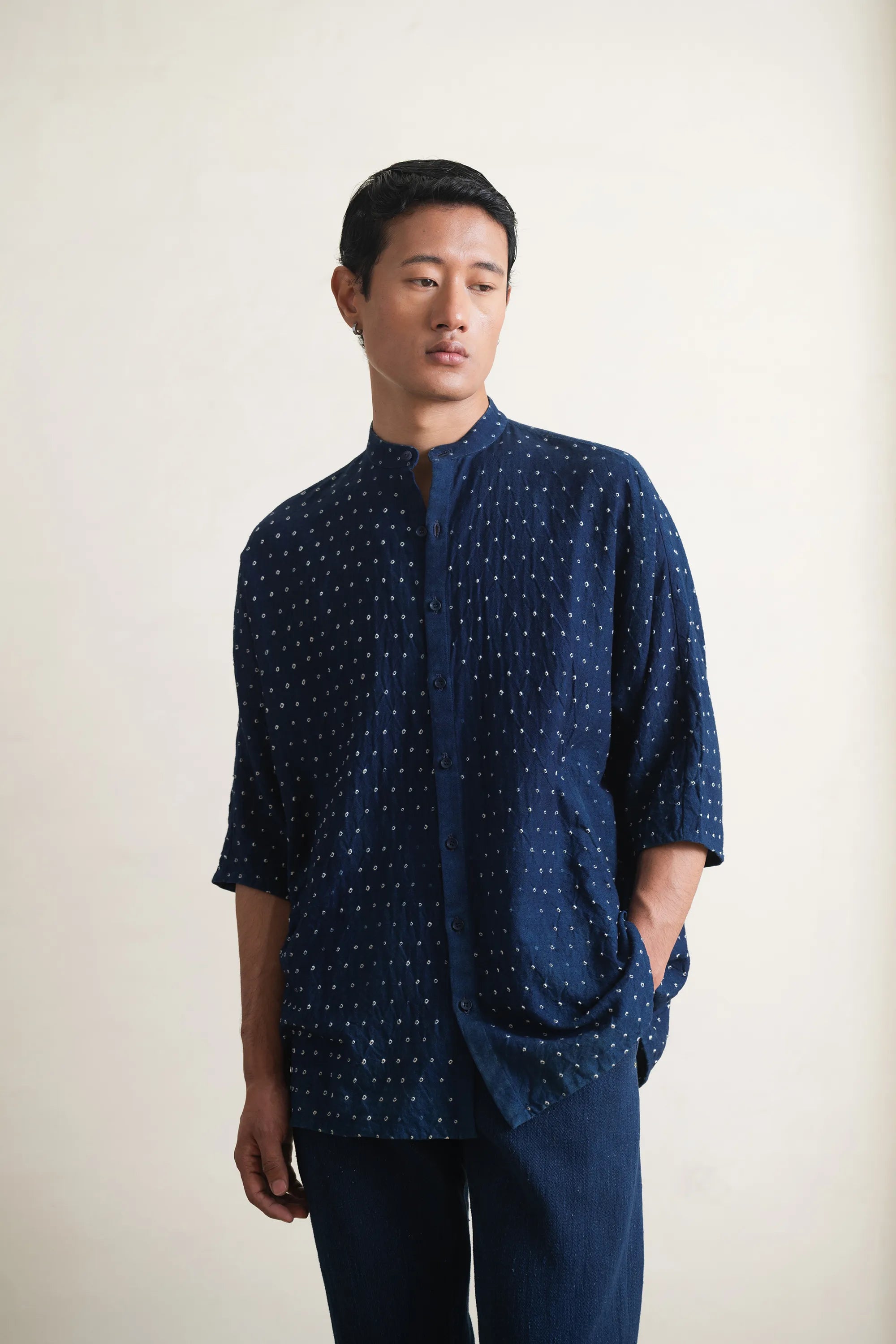 Man wearing a indigo bandhani shirt against a light grey background