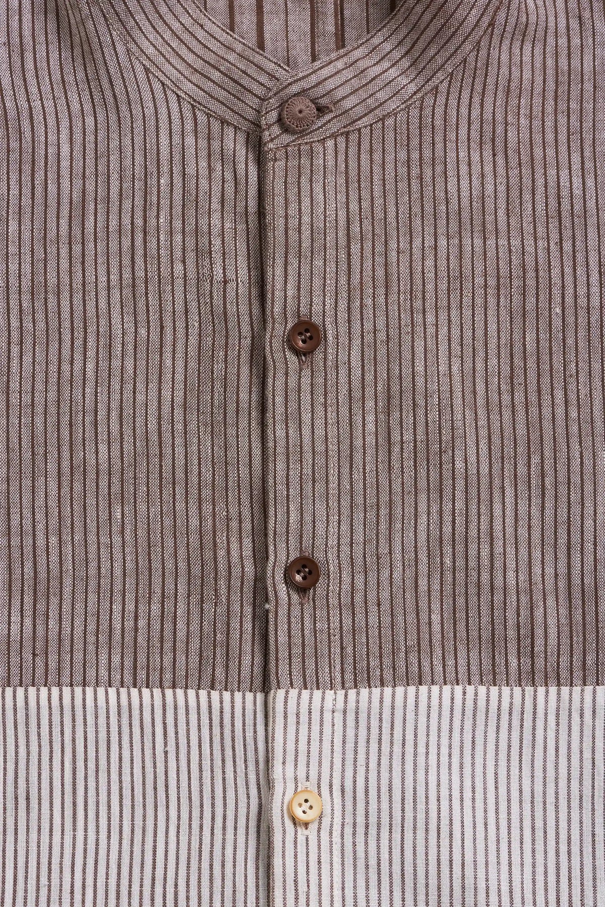 Close-up of a button-front garment with a vertical striped pattern in taupe-brown and off-white, featuring dark brown buttons and a light tan button near the bottom.