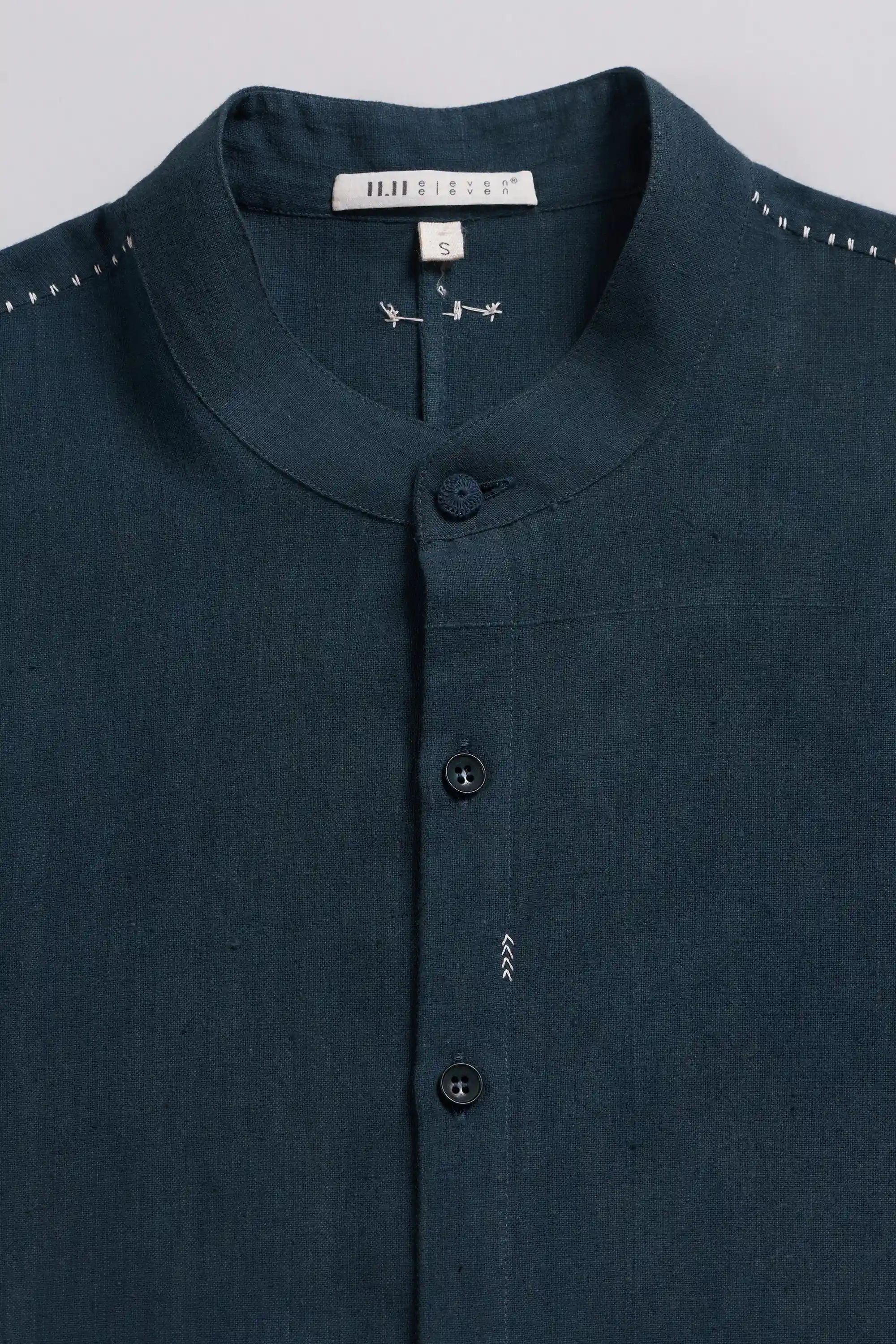 A close-up of a black indigo button-down shirt with a band collar.
