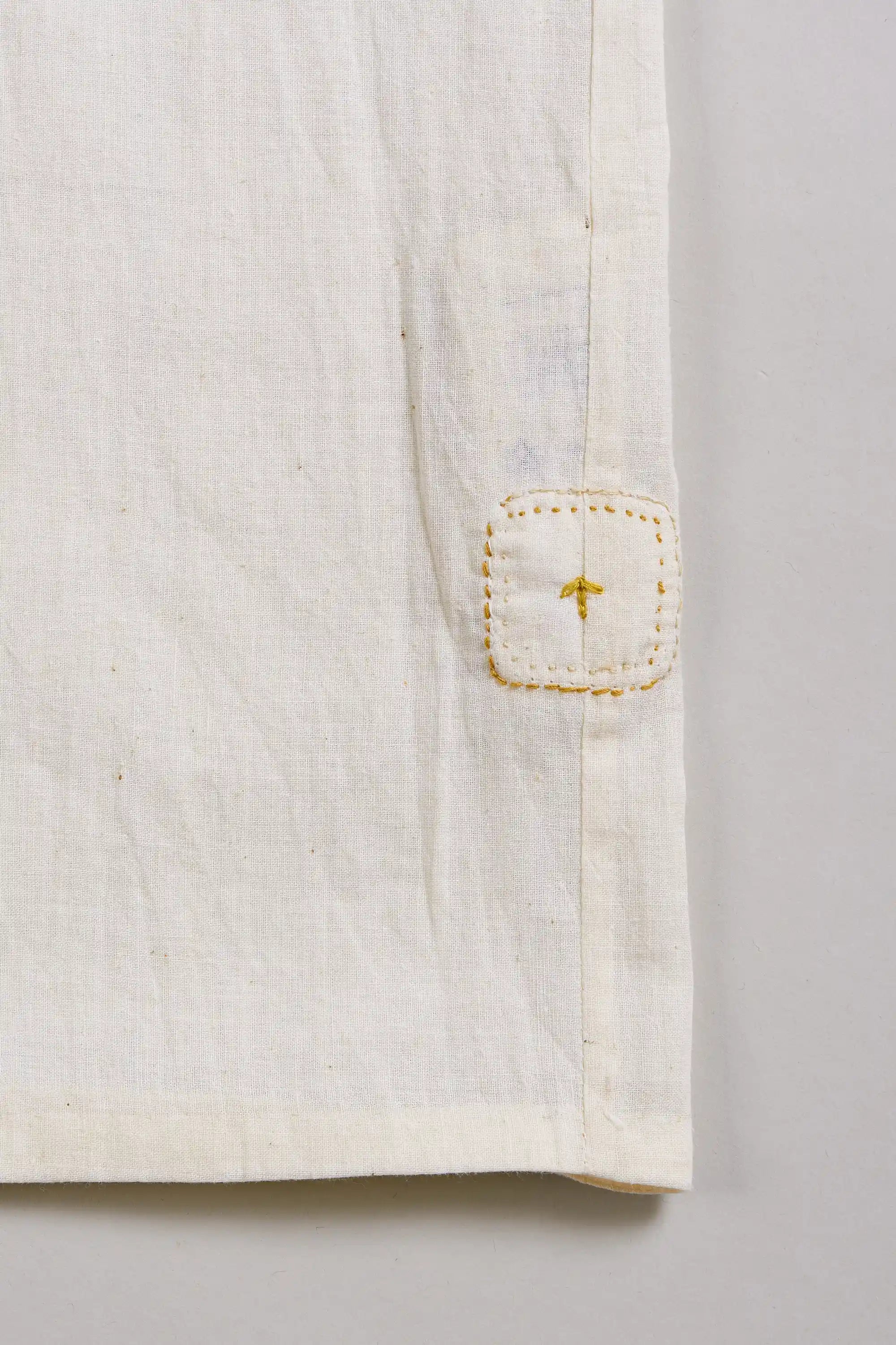 Close-up of a ecru shirt with a pehchanbox  on a light grey background