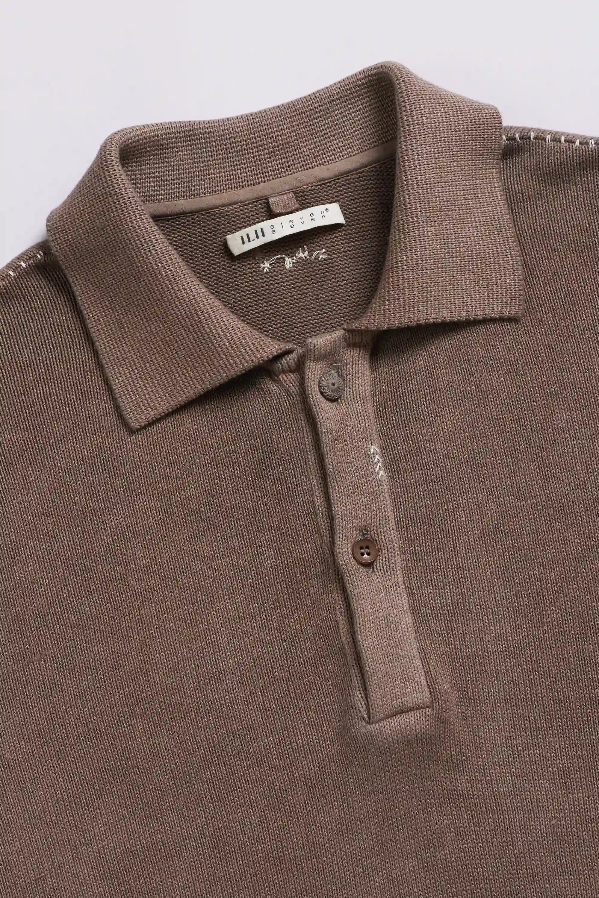 Brown polo t-shirt with a visible brand label and button on a light grey background