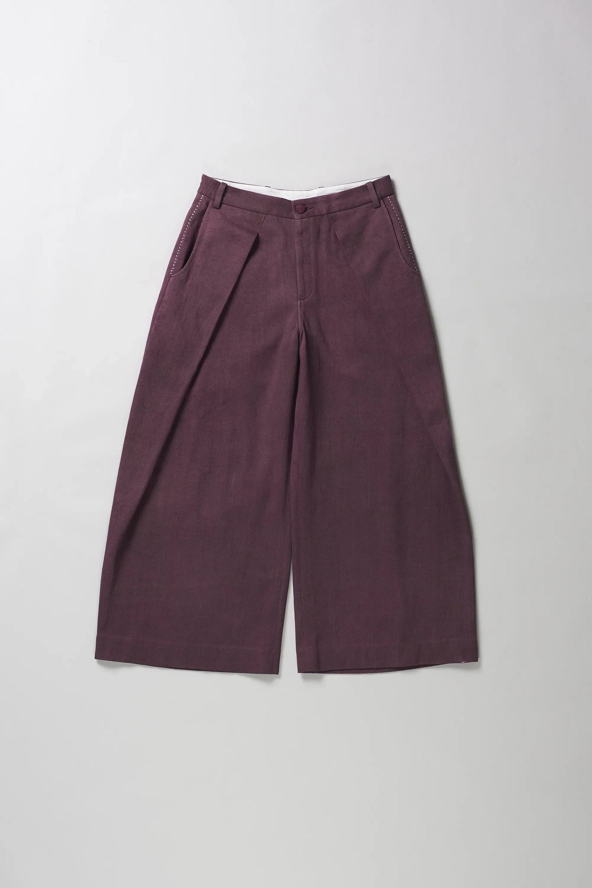A pair of wide-leg trousers in a purple color, laid flat against a light grey background.