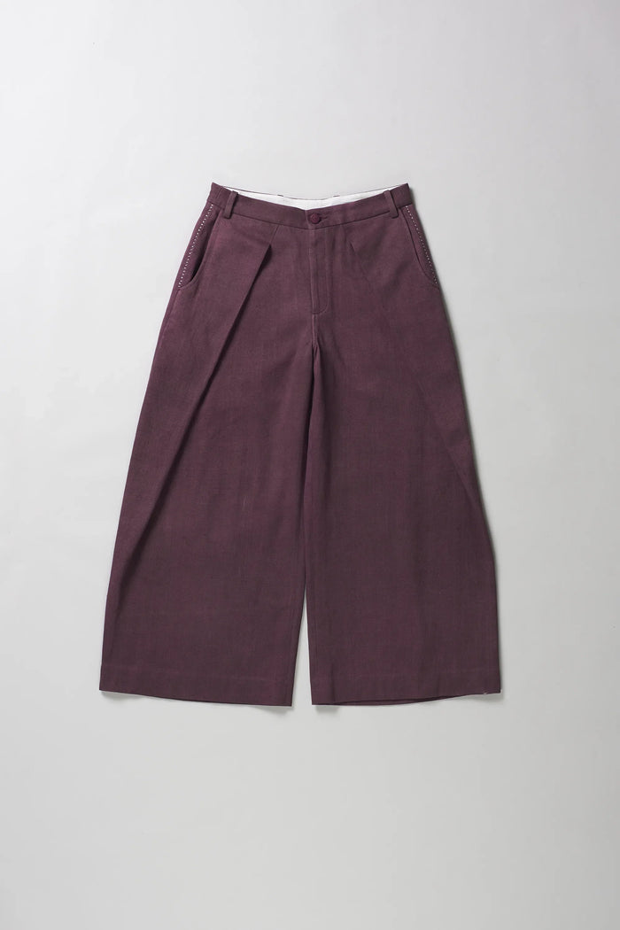 A pair of wide-leg trousers in a purple color, laid flat against a light grey background.