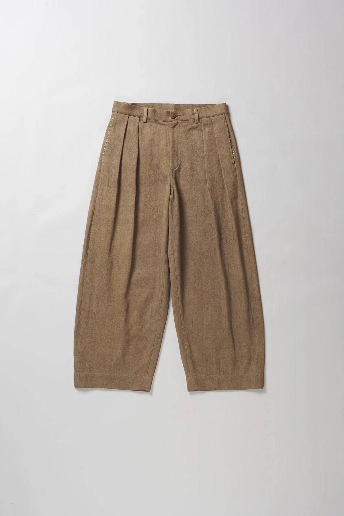 A pair of wide-leg trousers in a textured tan fabric, laid flat against a light grey background.
