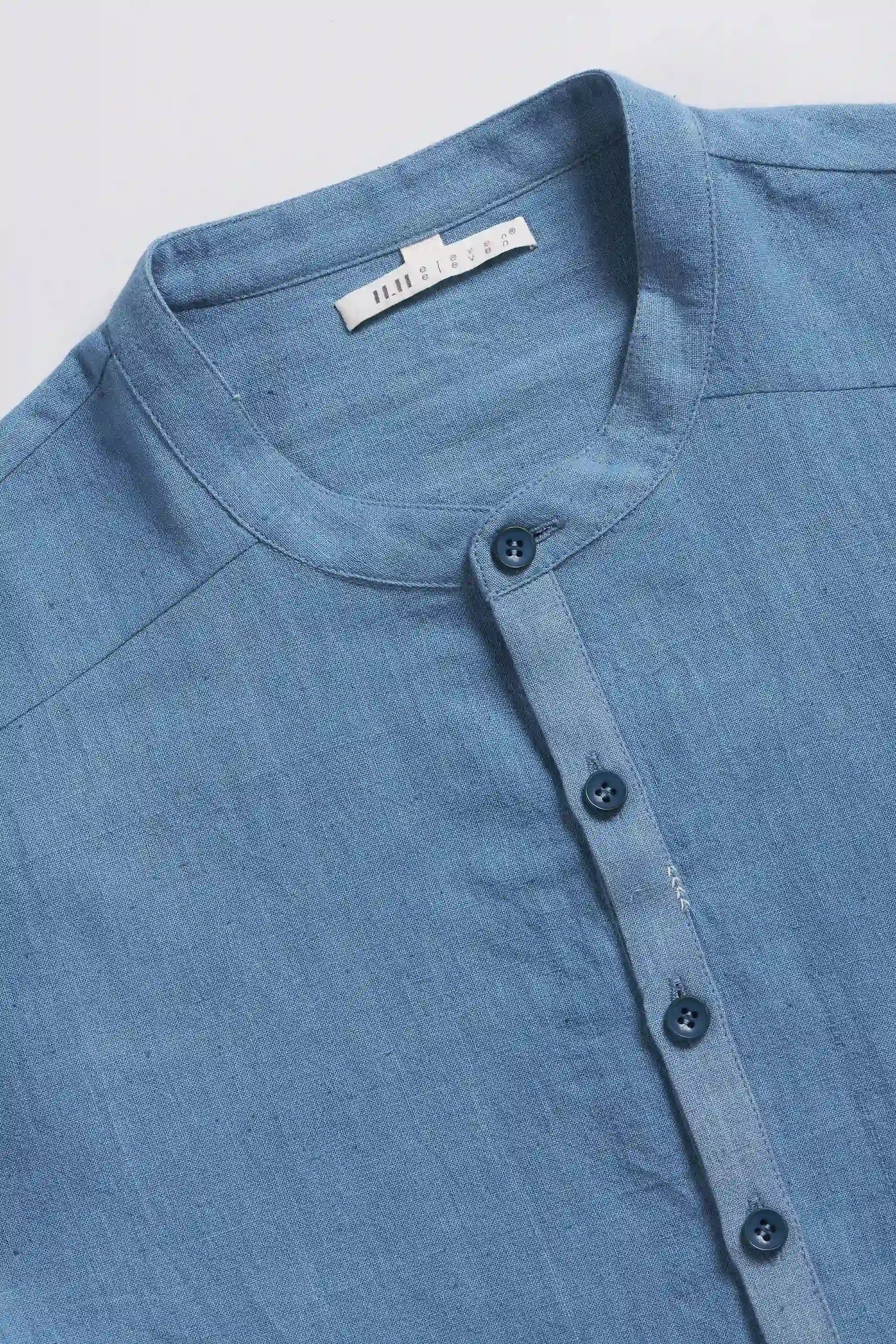 Close-up of a blue shirt with buttons on a light grey background