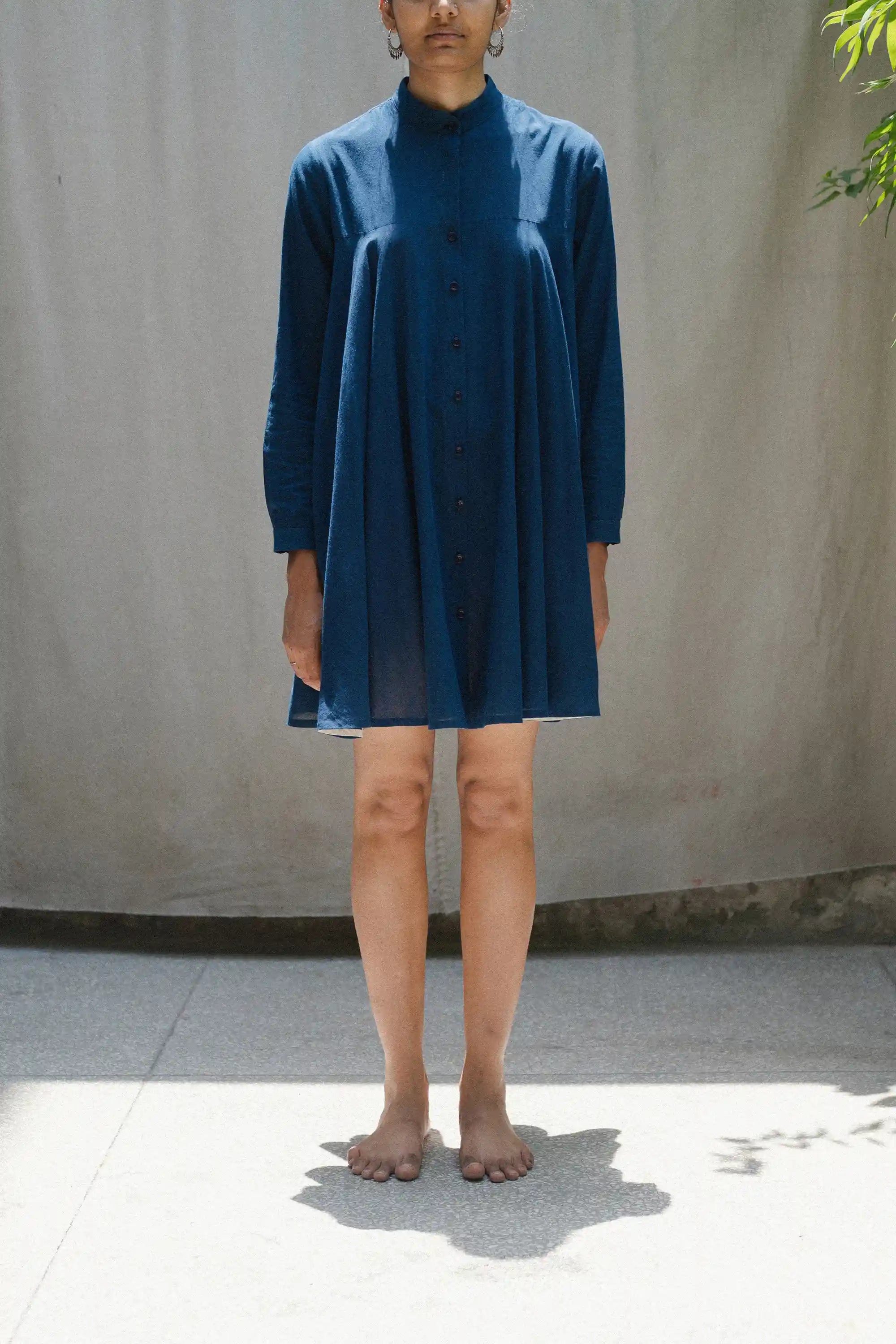 Person wearing a blue dress standing against a plain background