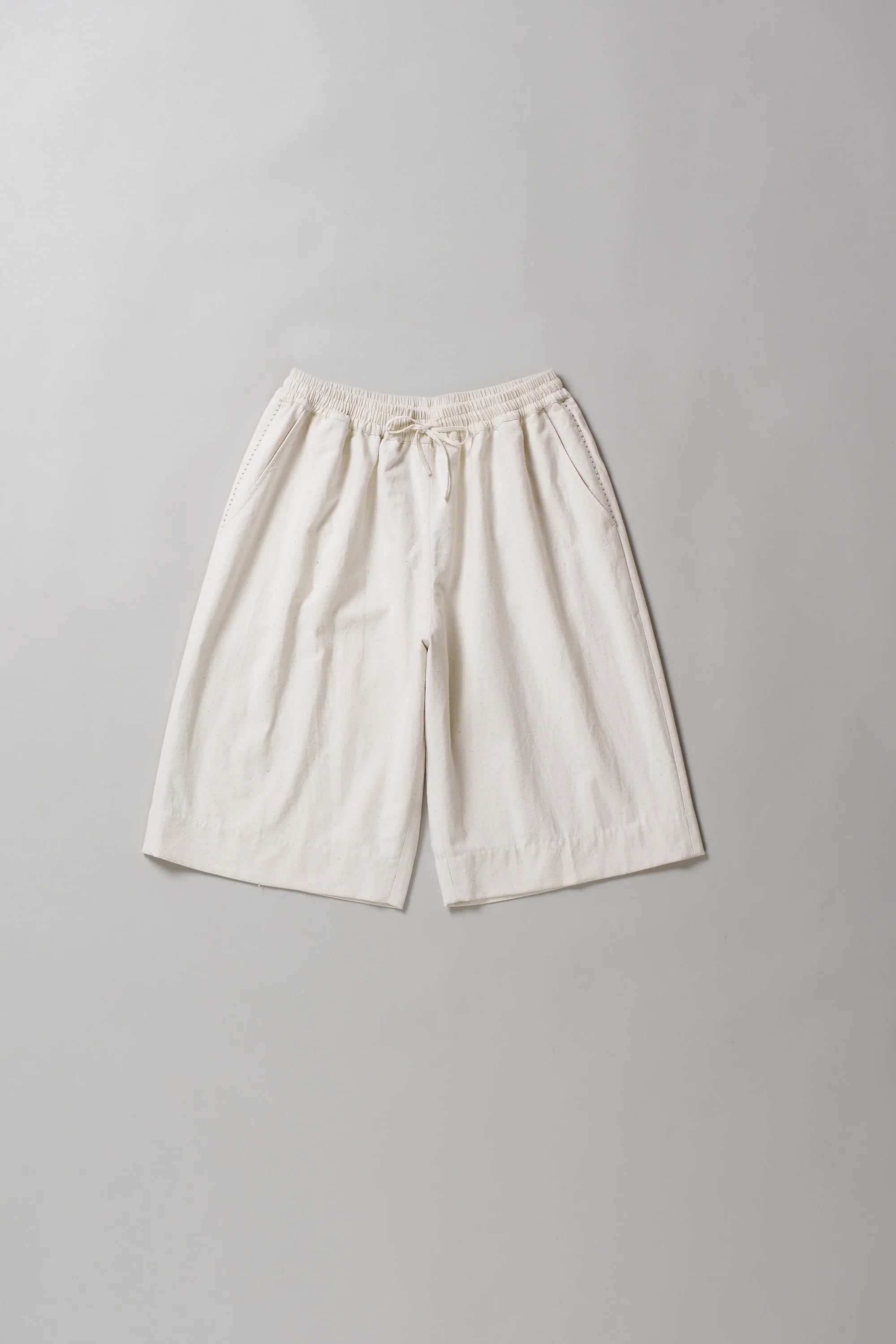 Front image of ecru cotton shorts on a grey background