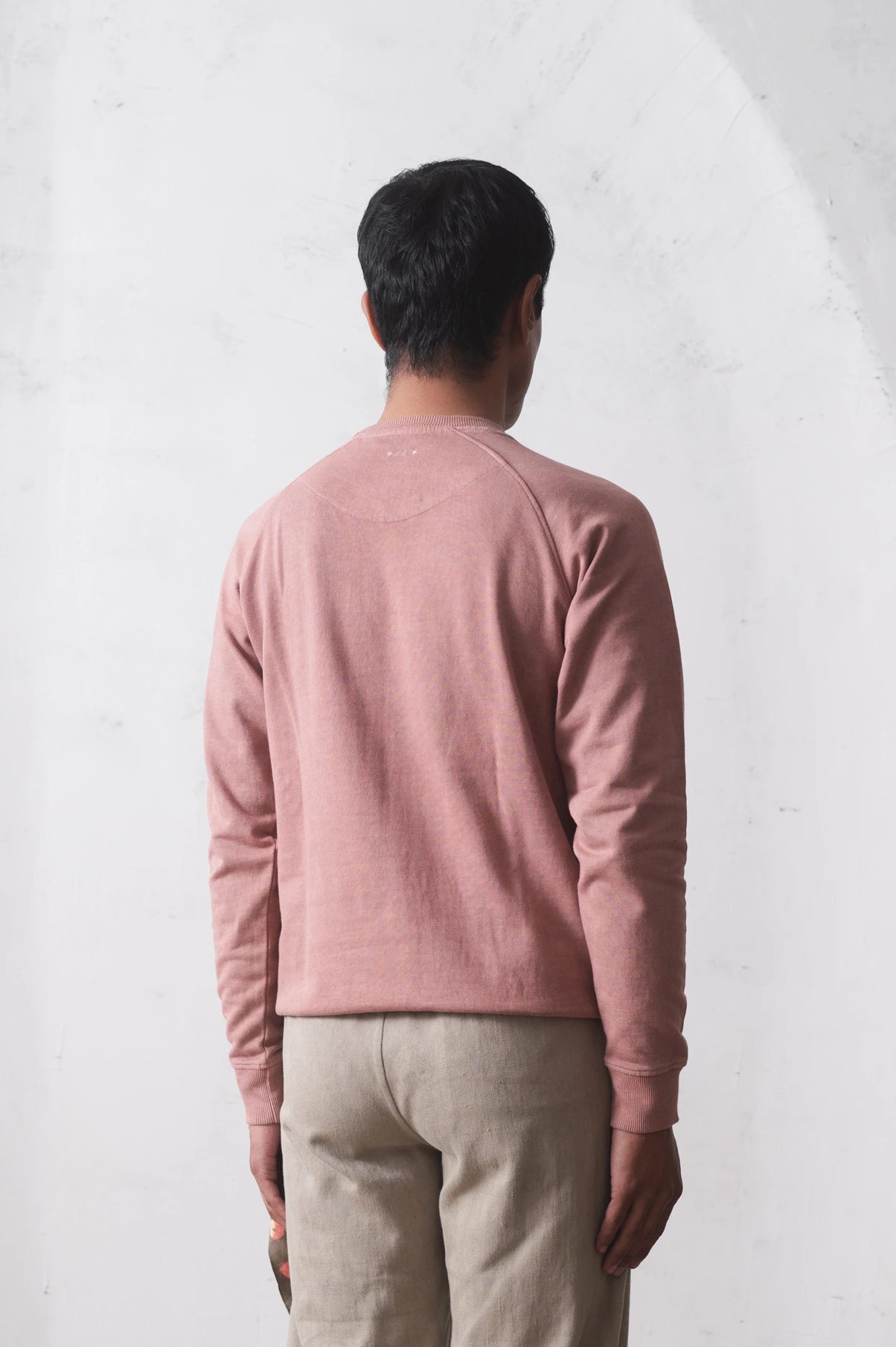 Person wearing a old rose long-sleeve sweatshirt and pants against a light grey background