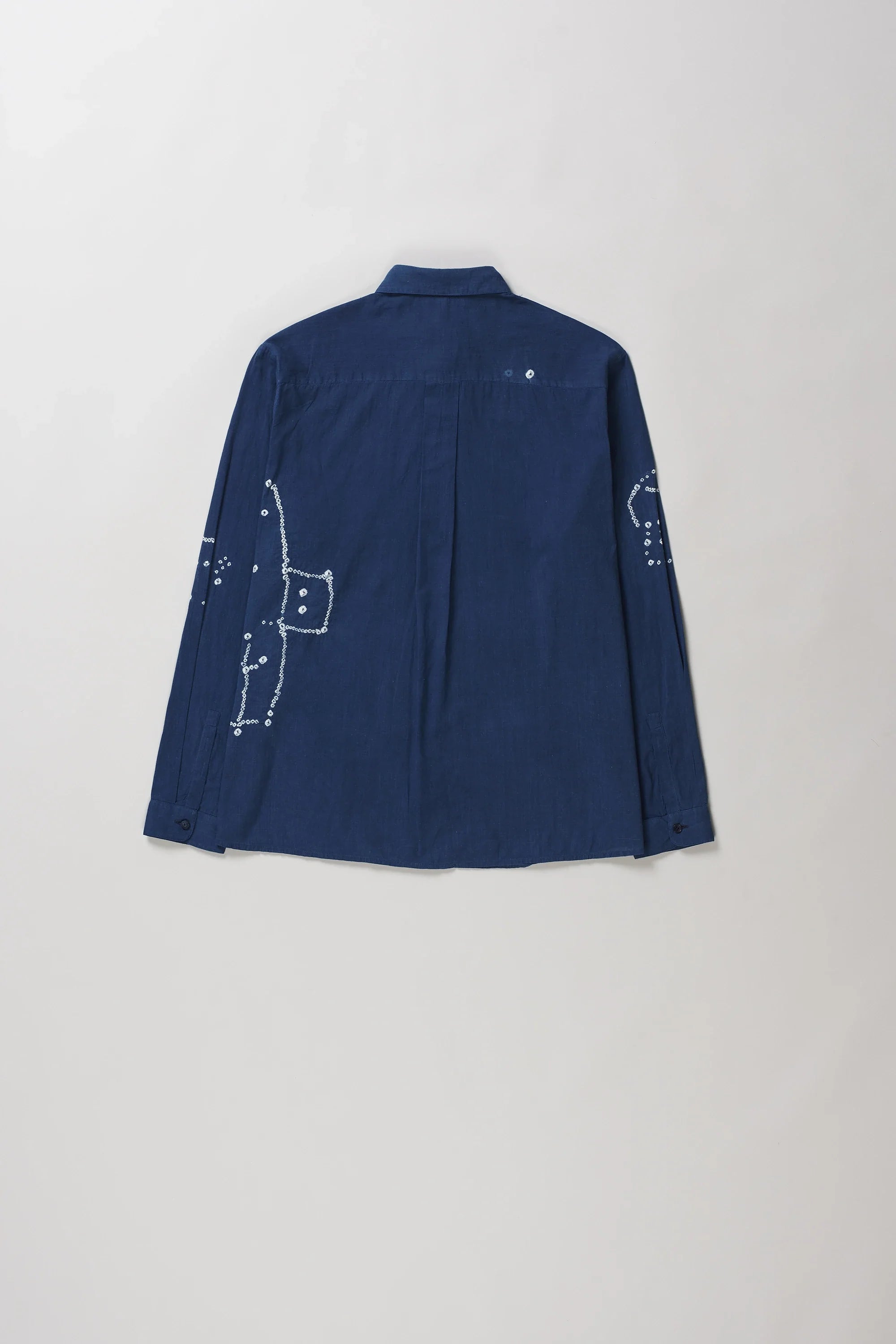 Back shot of medium indigo long-sleeve button-up shirt with bandhani, laid flat against a light grey background.