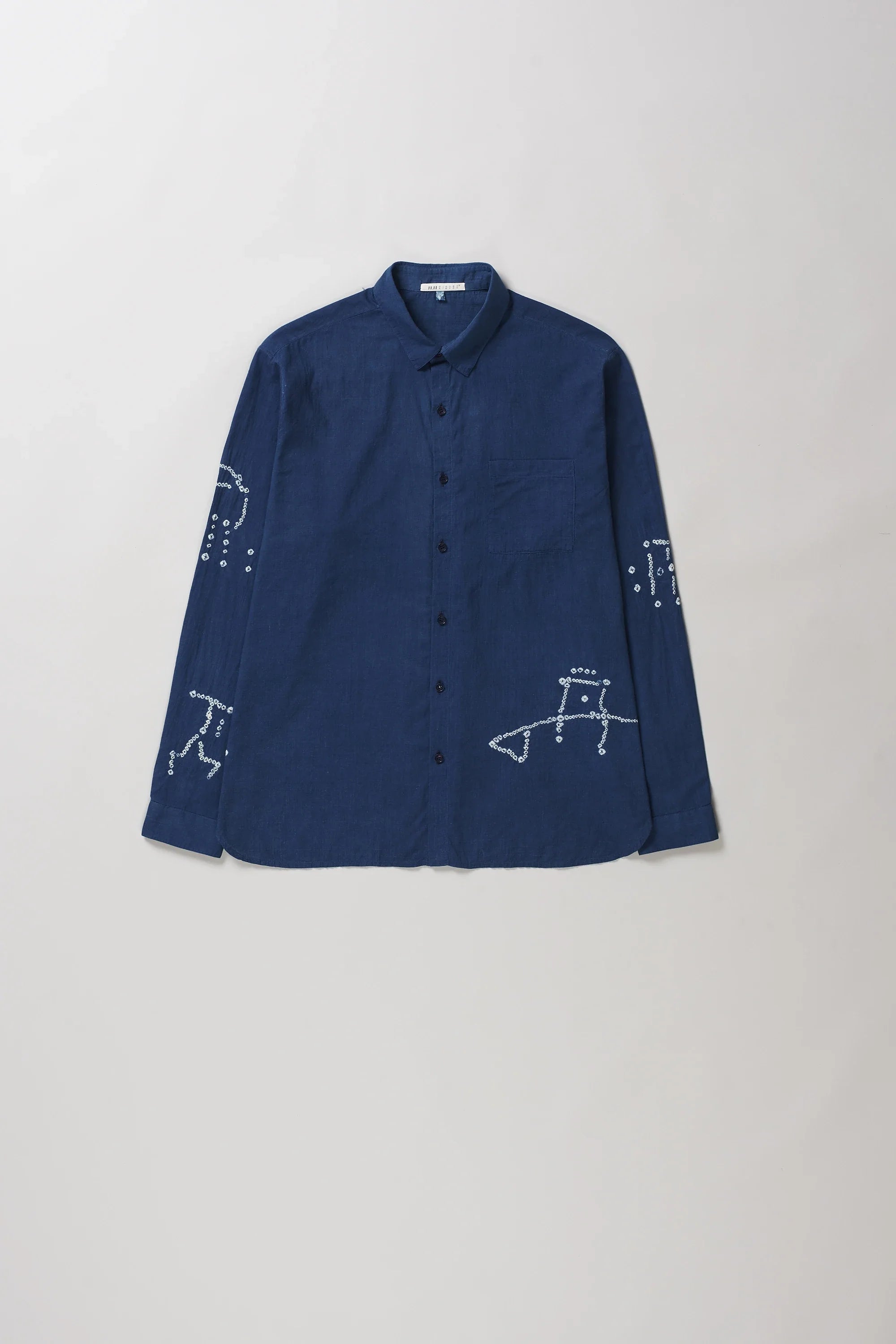 A medium indigo long-sleeve button-up shirt with bandhani, laid flat against a light grey background.