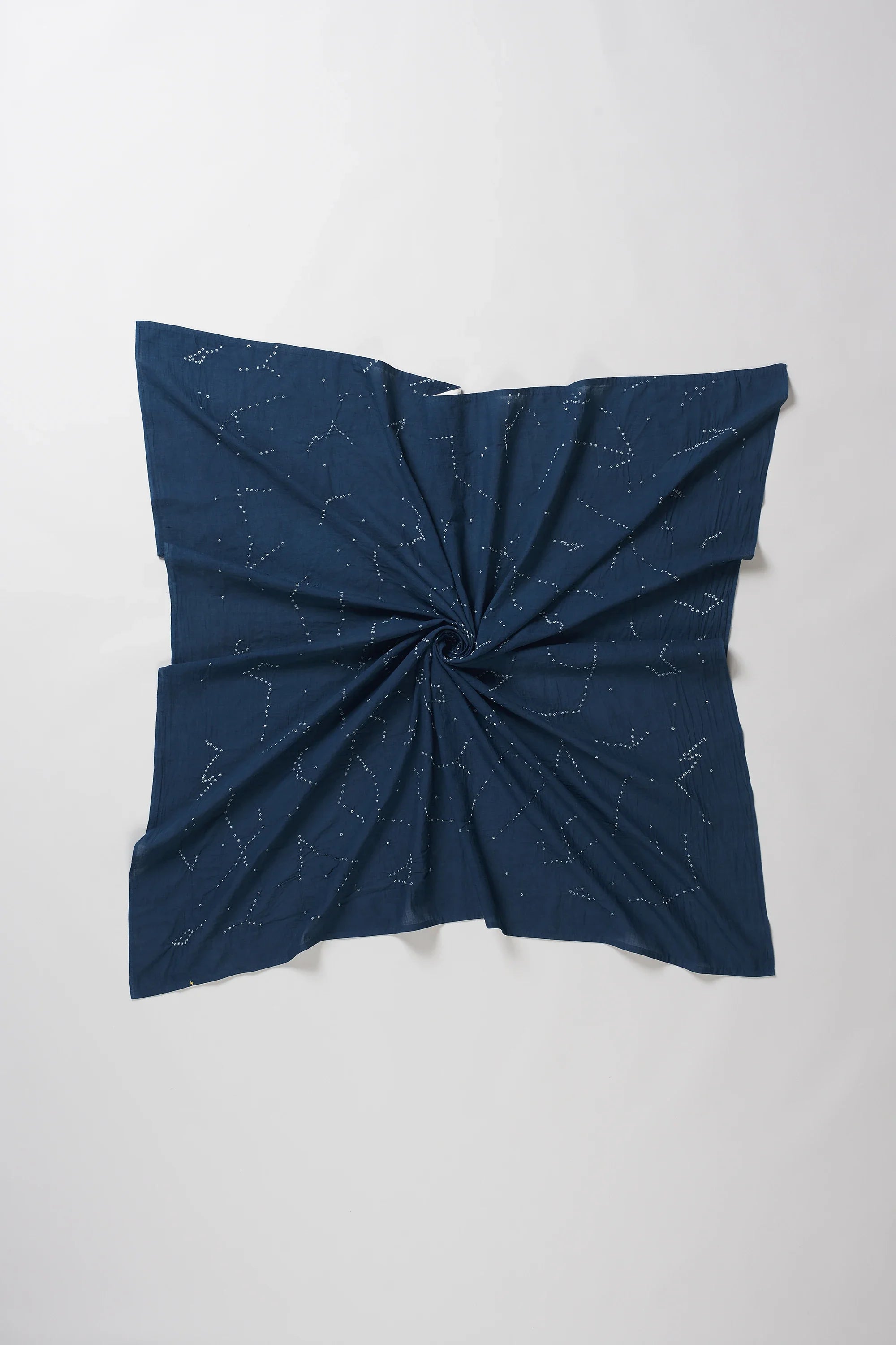 A space blue fabric scarf or bandana featuring a white constellation print, styled with a central twist on a light grey background.