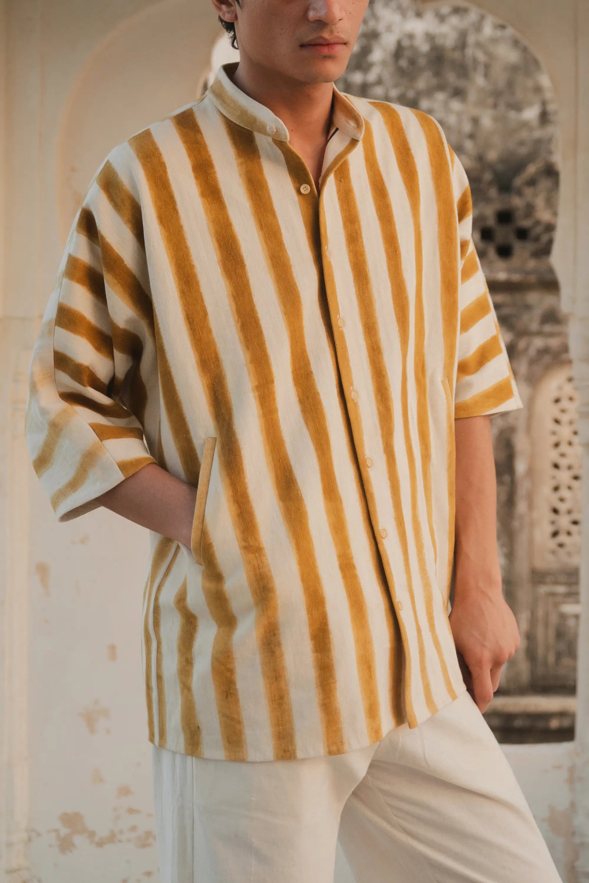 Person wearing a yellow and white striped shirt with a blurred architectural background