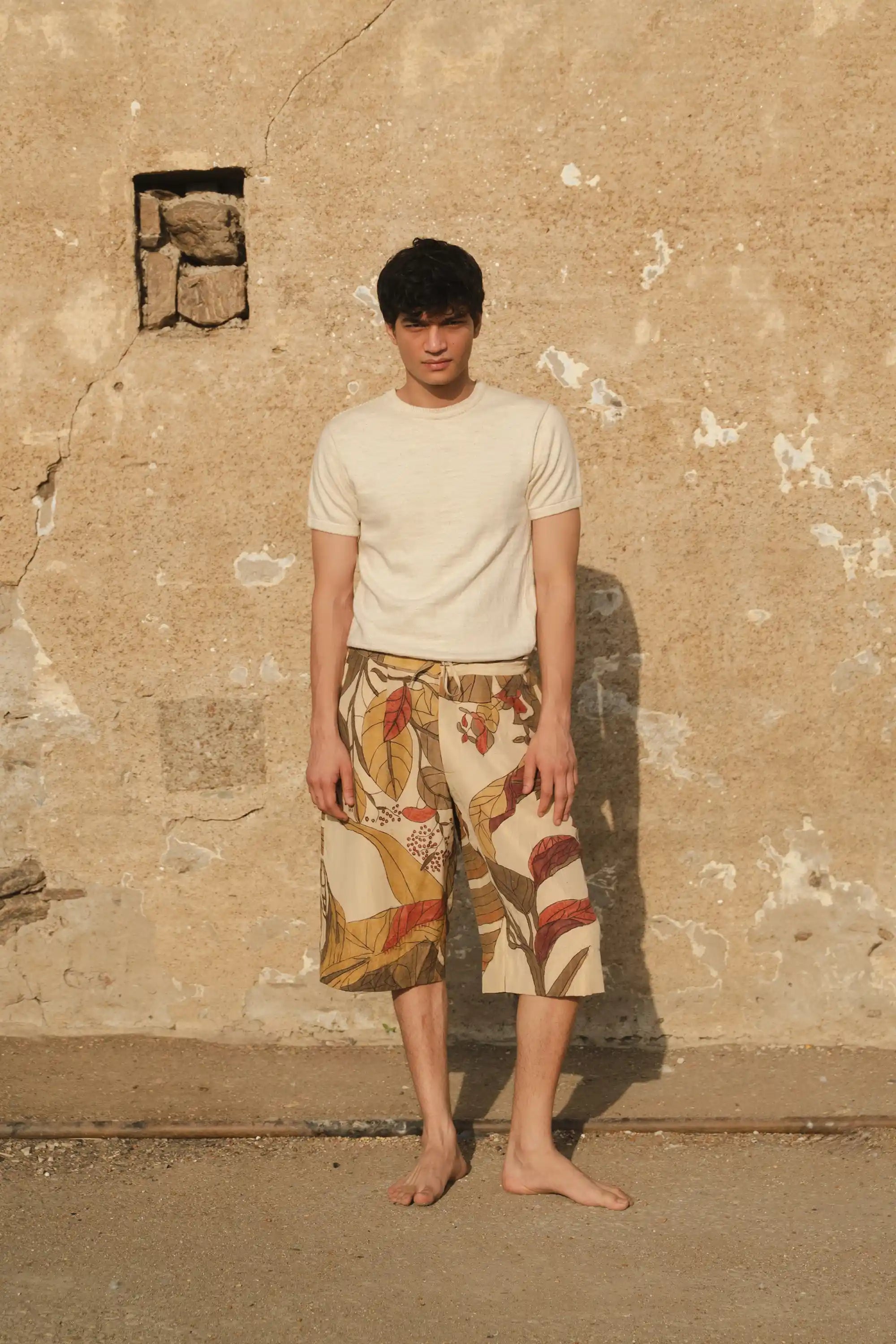 A man wearing ecru t-shirt with hand painted shorts