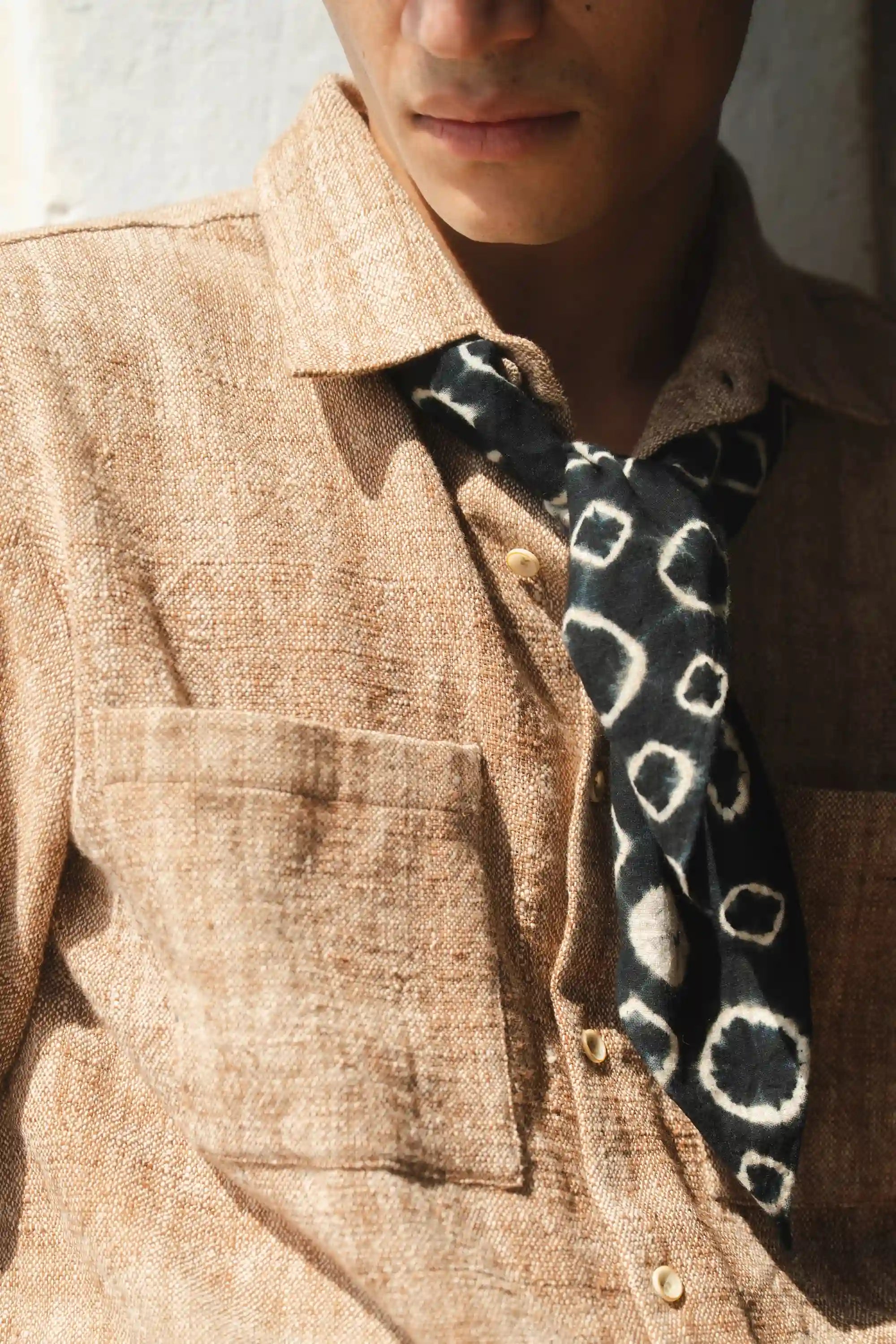 Person wearing a black hand shibori bandana with a beige shirt 