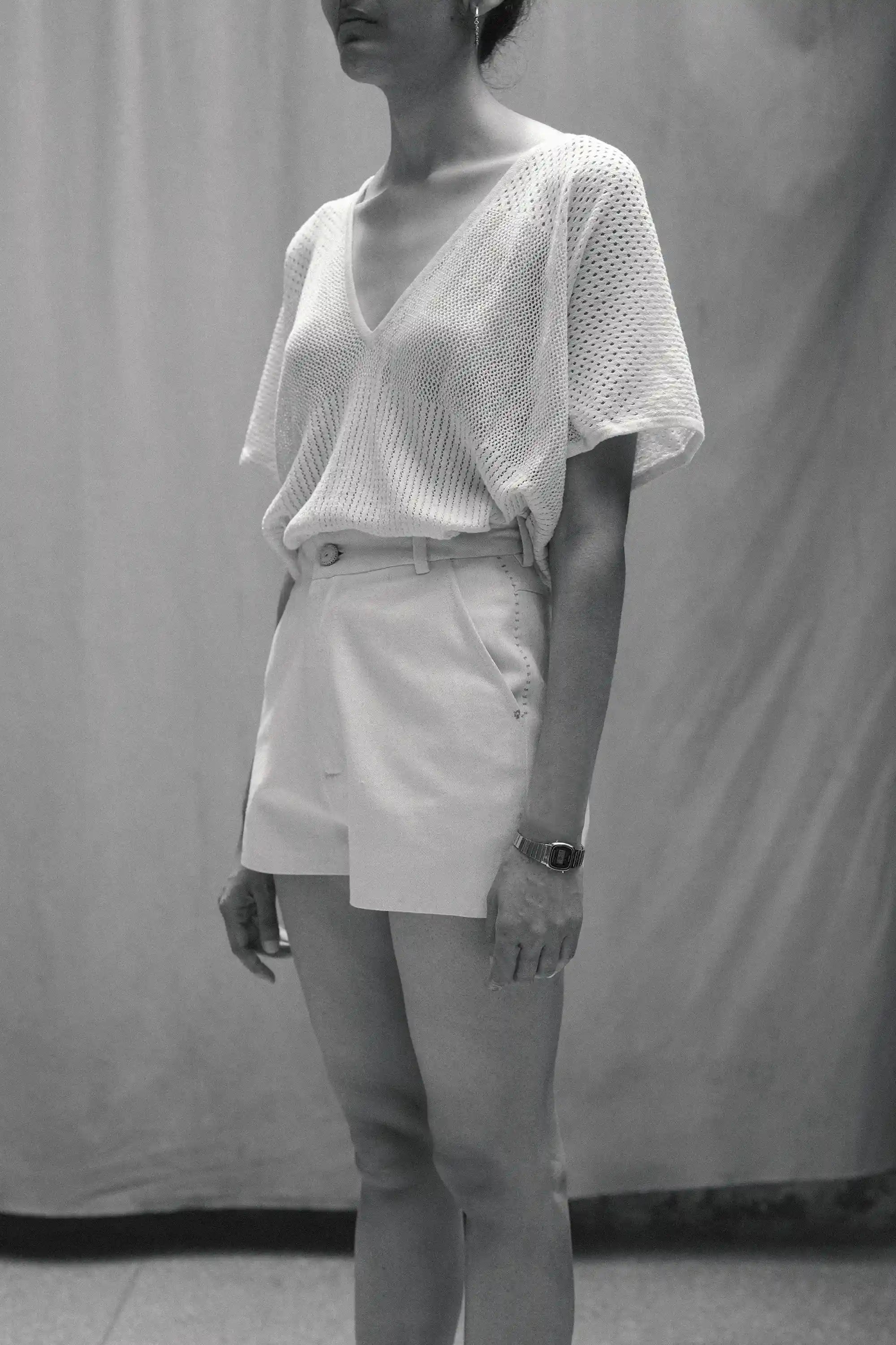 Person wearing a white top and shorts against a plain background