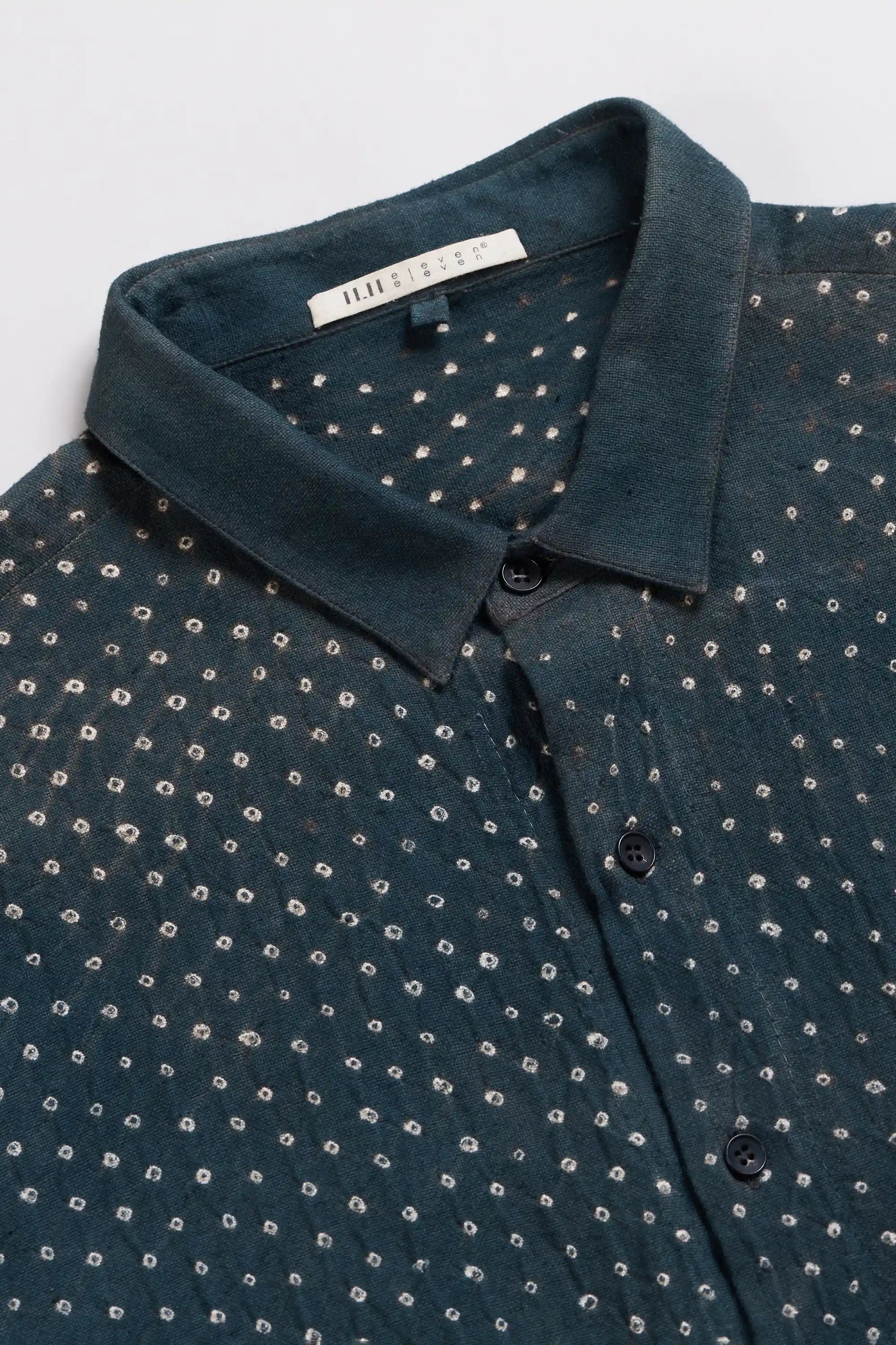 Close-up of a midnight indigo collared shirt with a small white dot bandhani and a visible neck label.