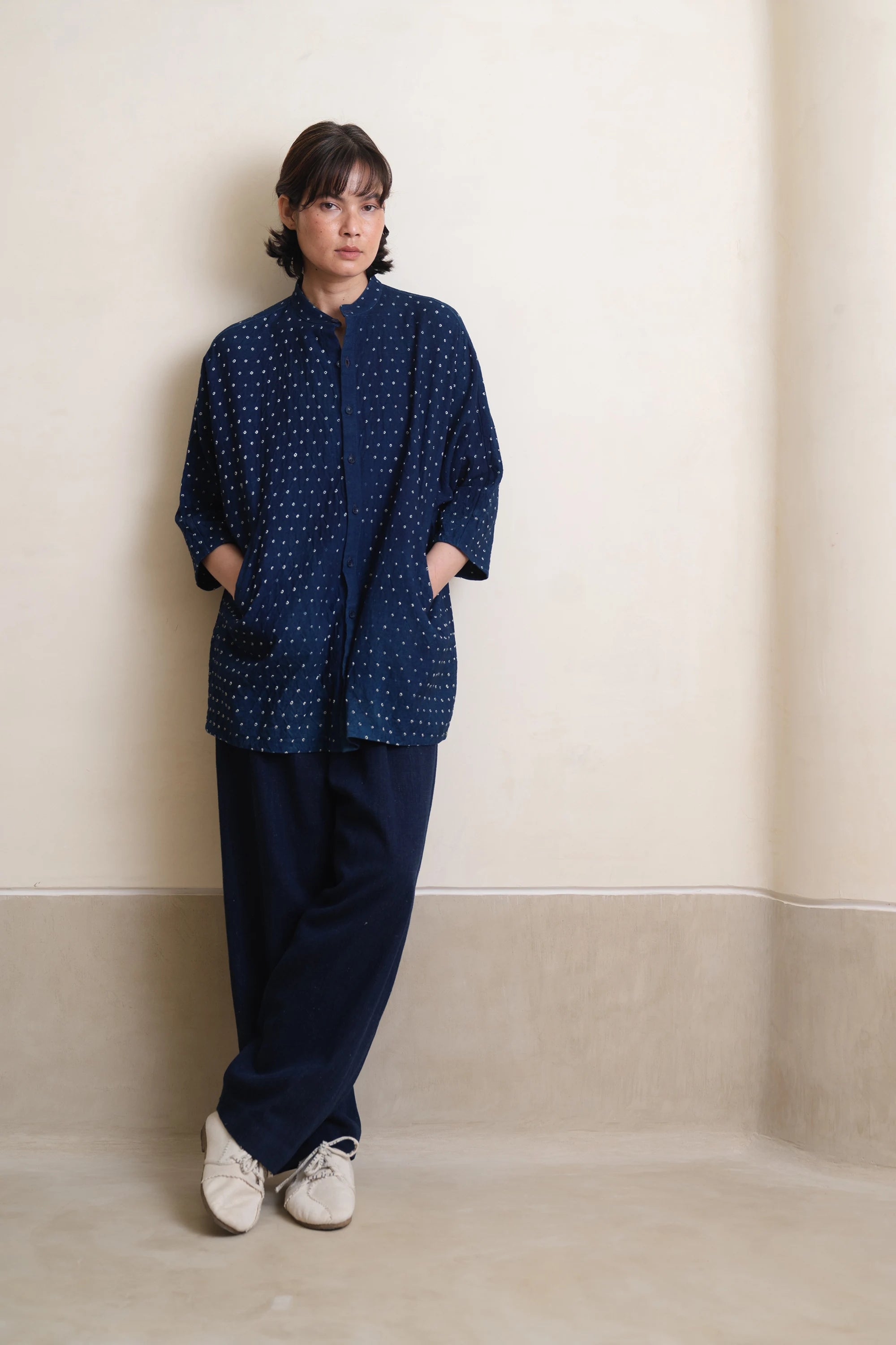 Woman wearing a indigo bandhani shirt with against plain background