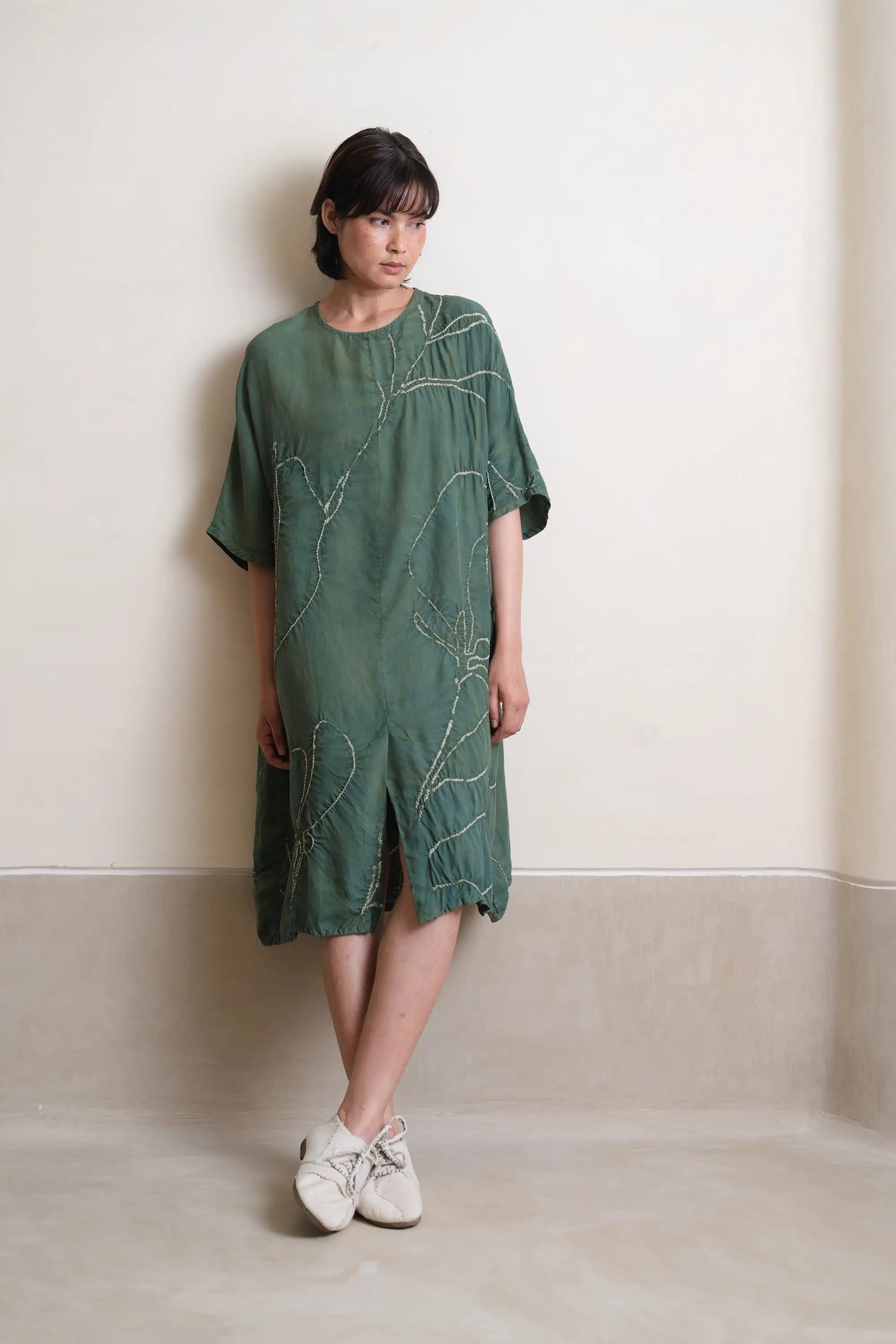 A woman wearing silk olive green dress