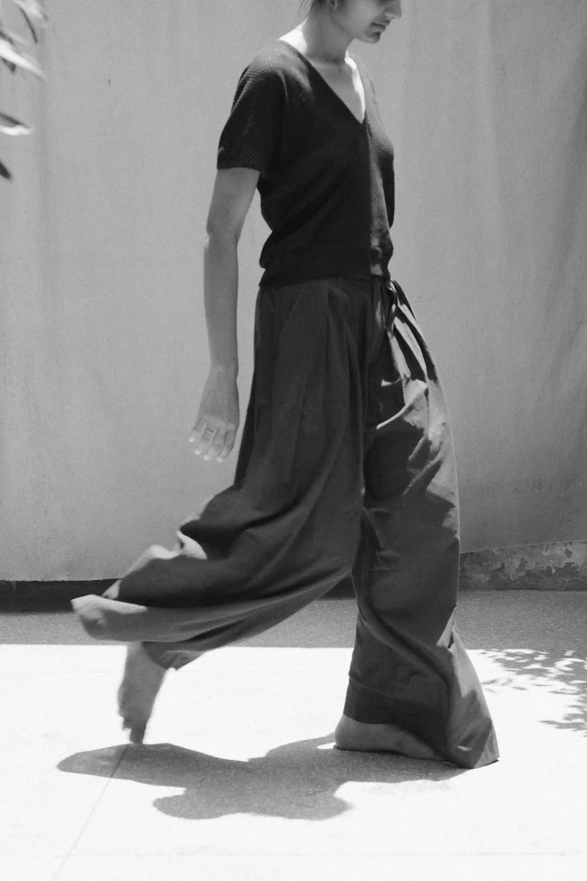Person wearing a top and wide-leg pants standing against a plain background.