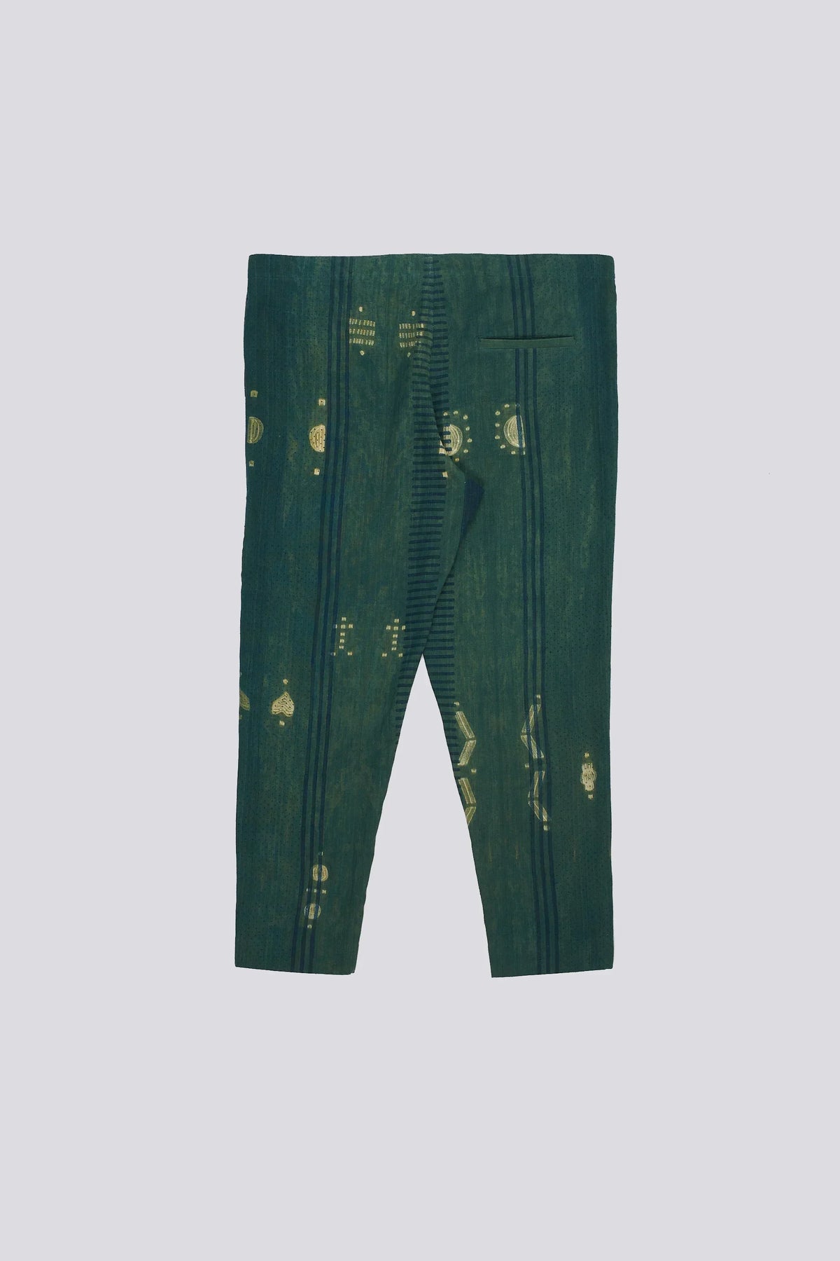 Back shot of bottle green pants with yellow patterns shibori a plain background
