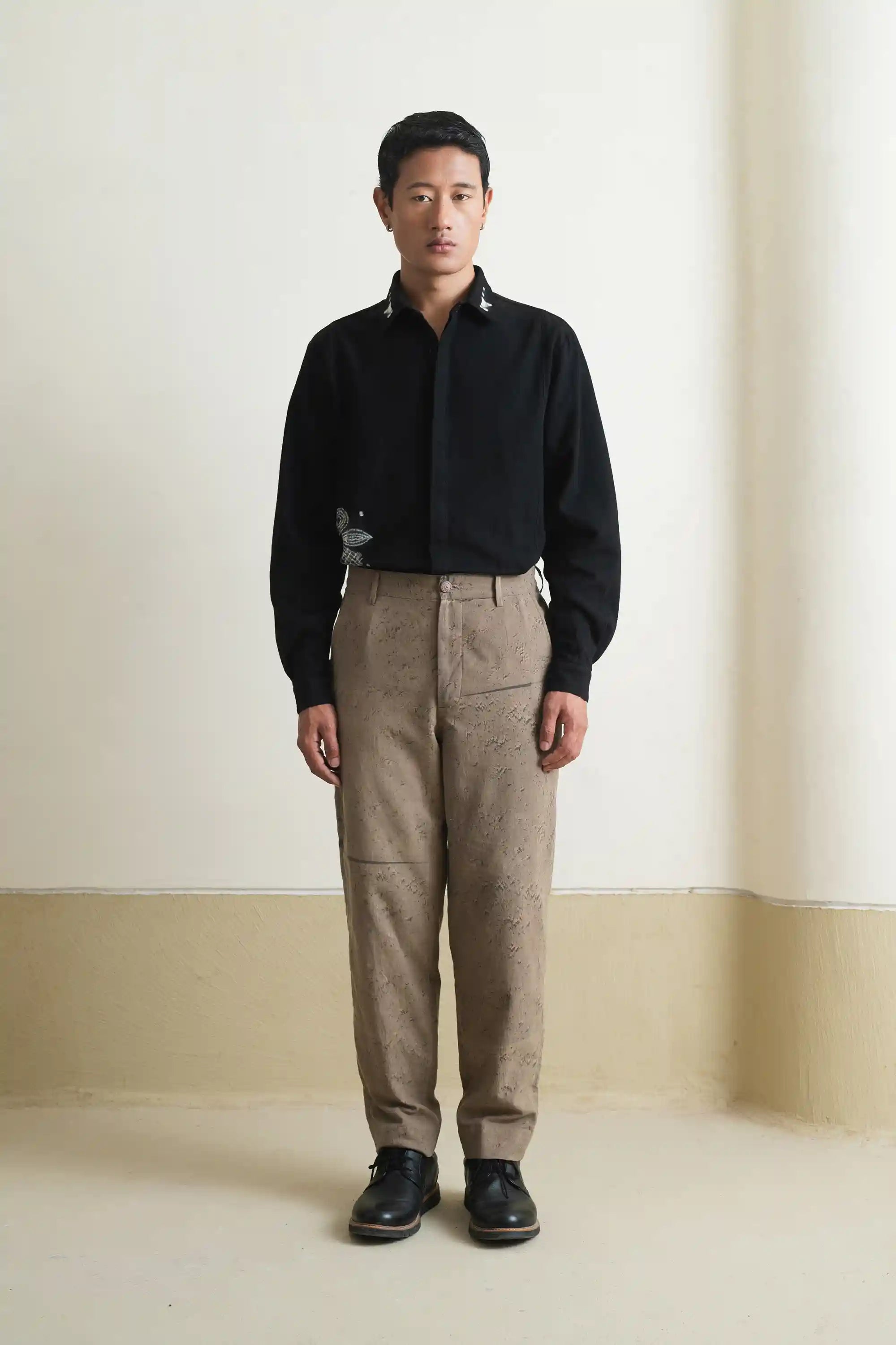 A man wearing khaki green cotton pant black shibori shirt