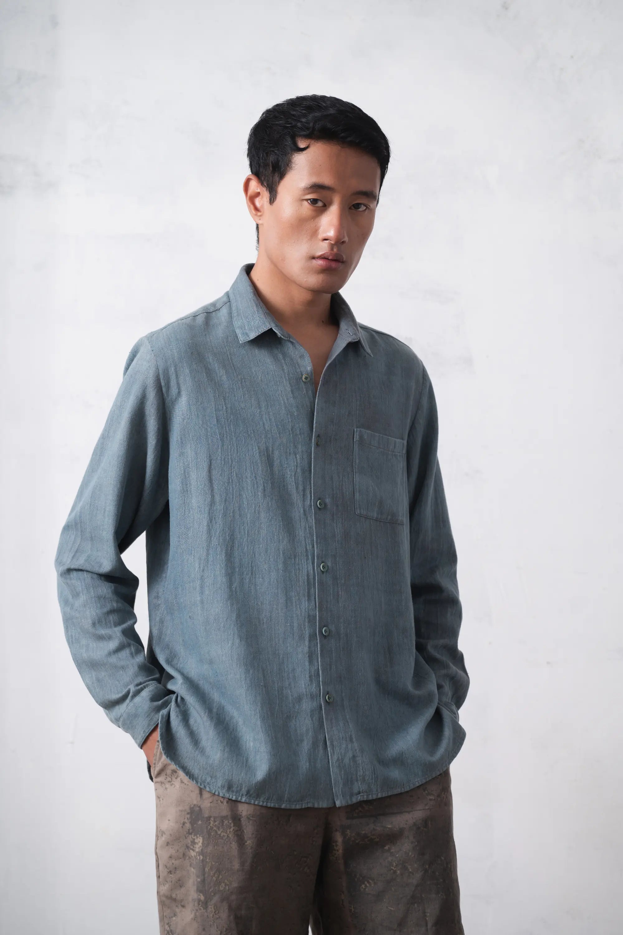 Man wearing a light blue denim shirt against a plain background
