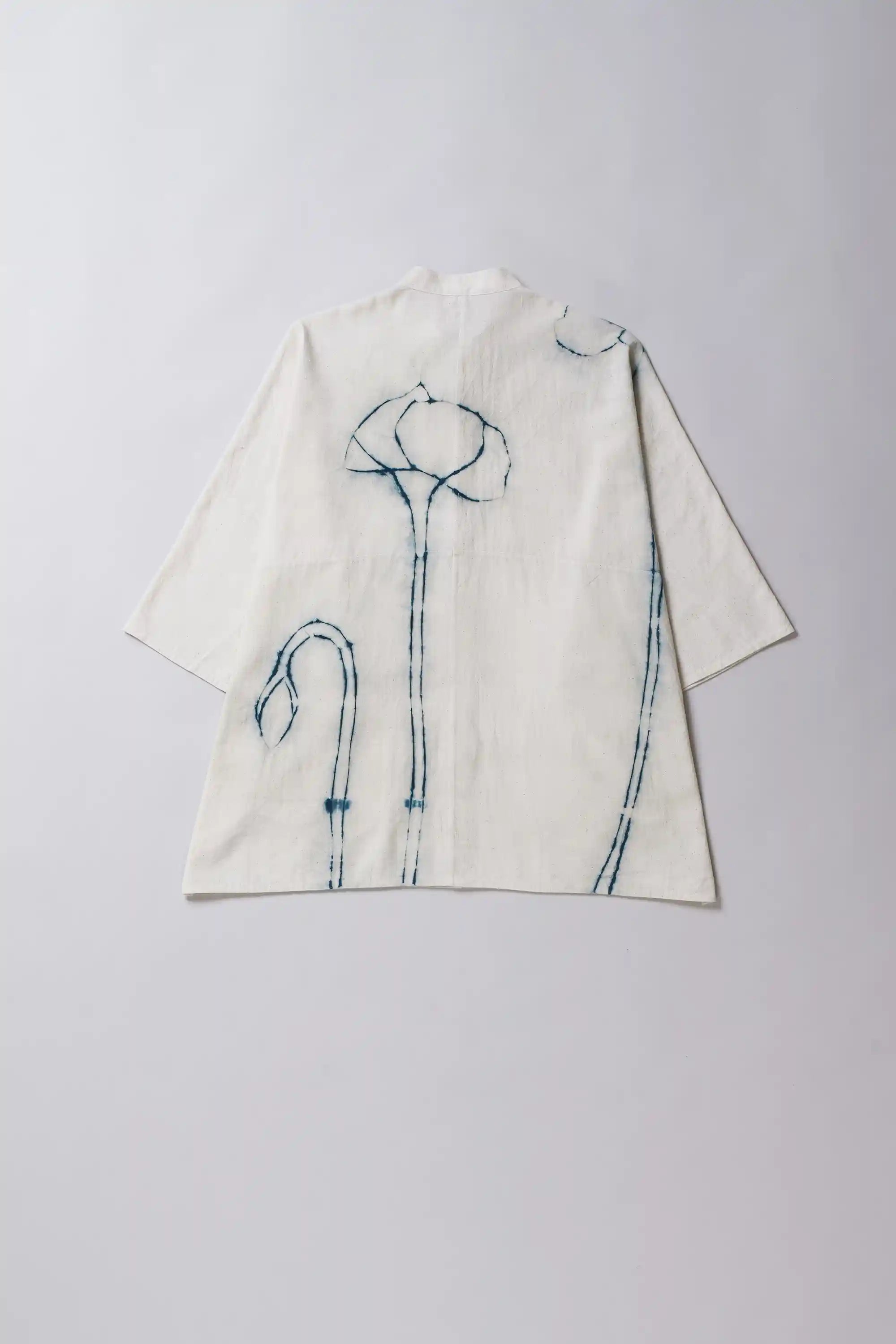 Back image of ecru shirt with shibori artwork on a grey background