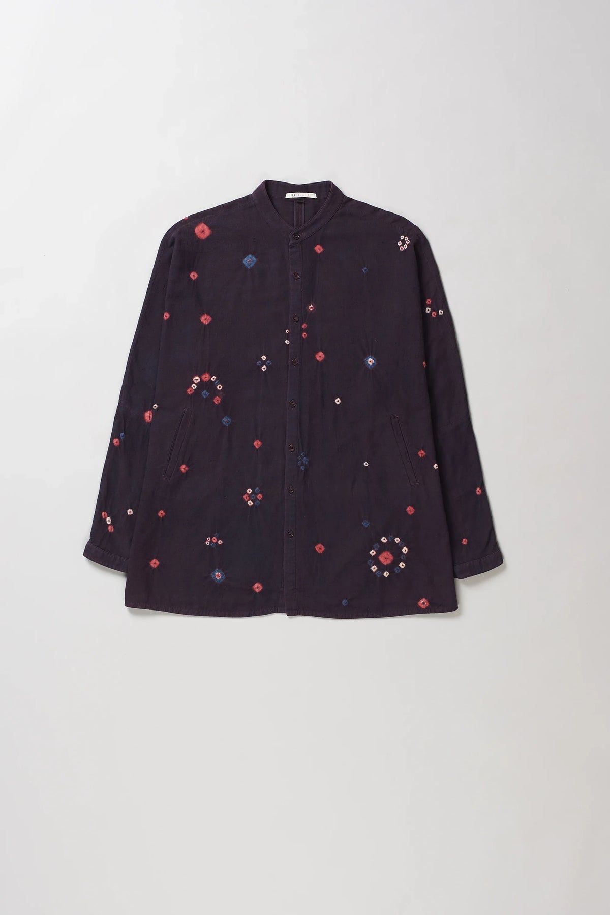 A purple red button-up shirt with red and blue bandhani floral motifs, displayed flat against a light grey background.