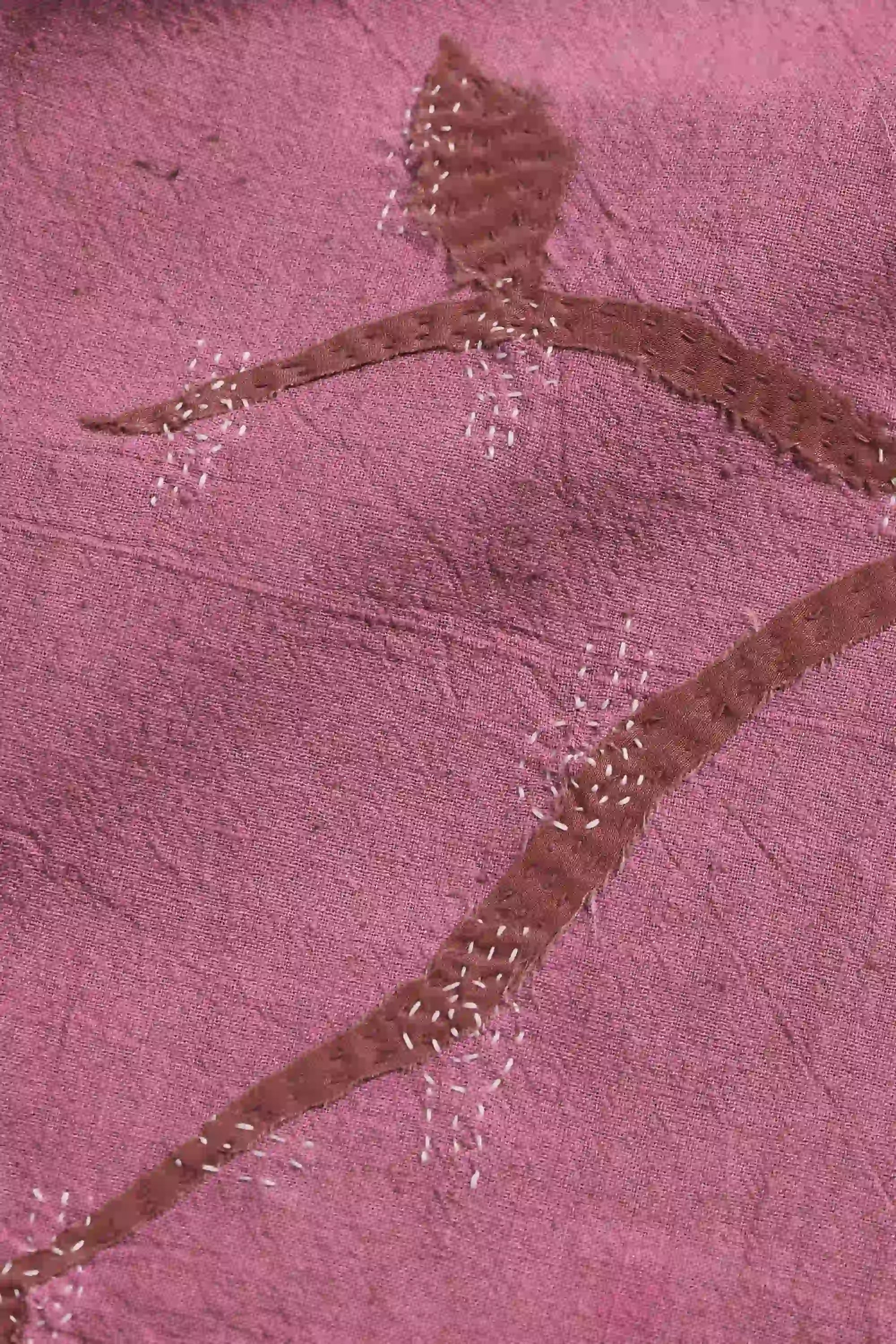 Close-up of a pink fabric with a decorative brown pattern