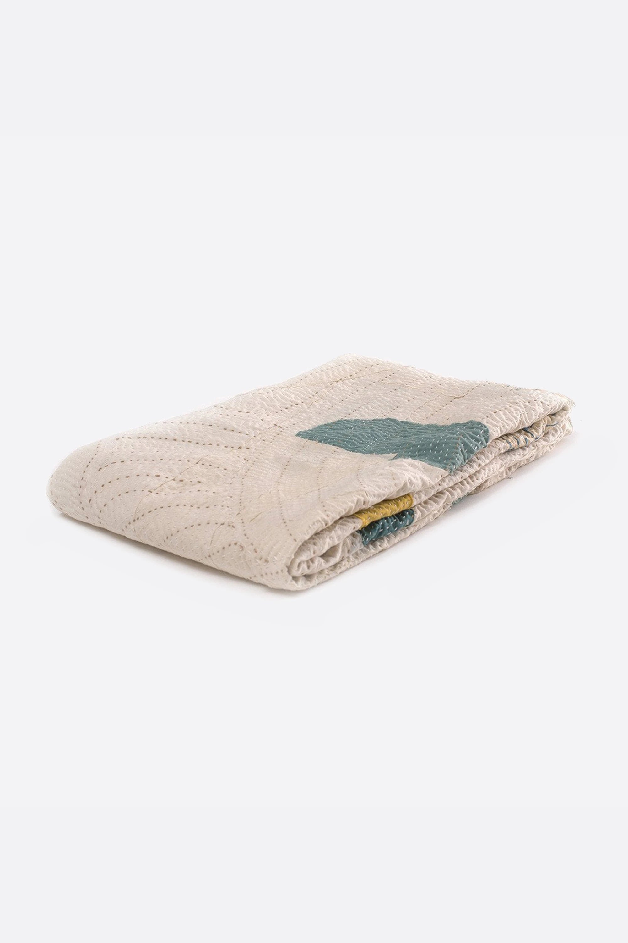 Folded ecru quilt on a grey background