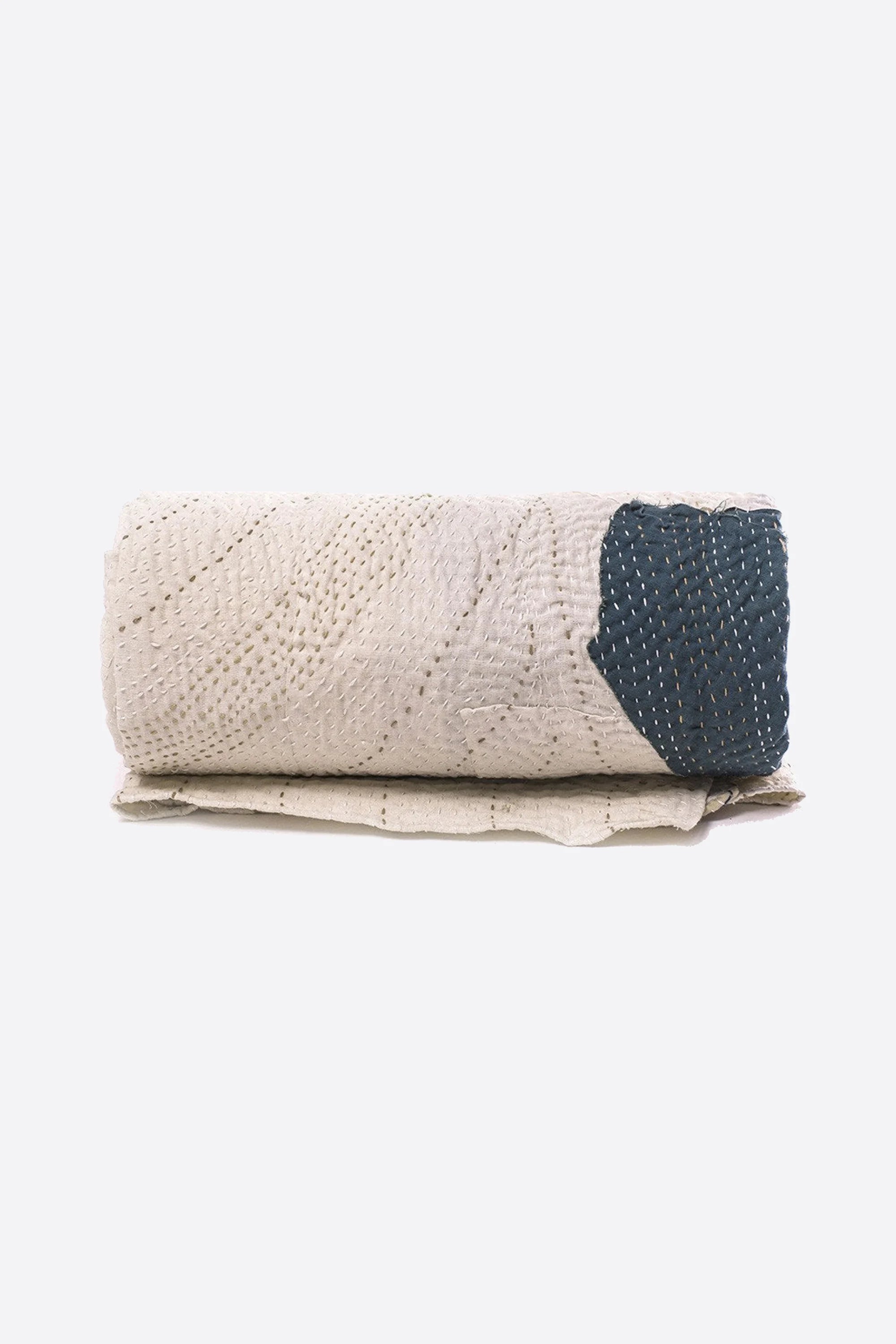 Ecru cotton kantha quilt roll on a white background